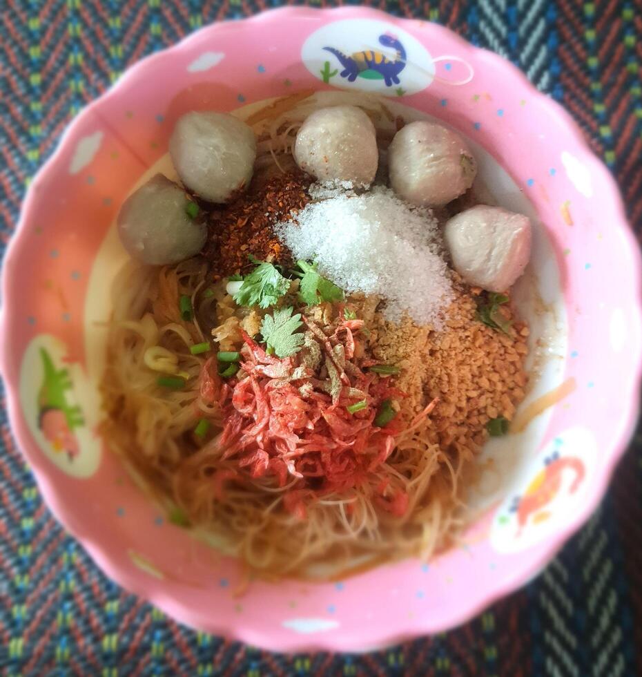 Dry noodles, a delicious Thai food that is sold on the streets of Thailand. The food is decorated with dried shrimp and meatballs photo