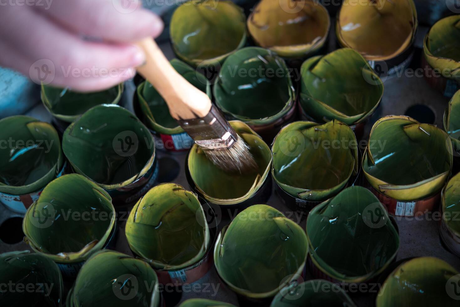 A person is painting green cups with a brush photo