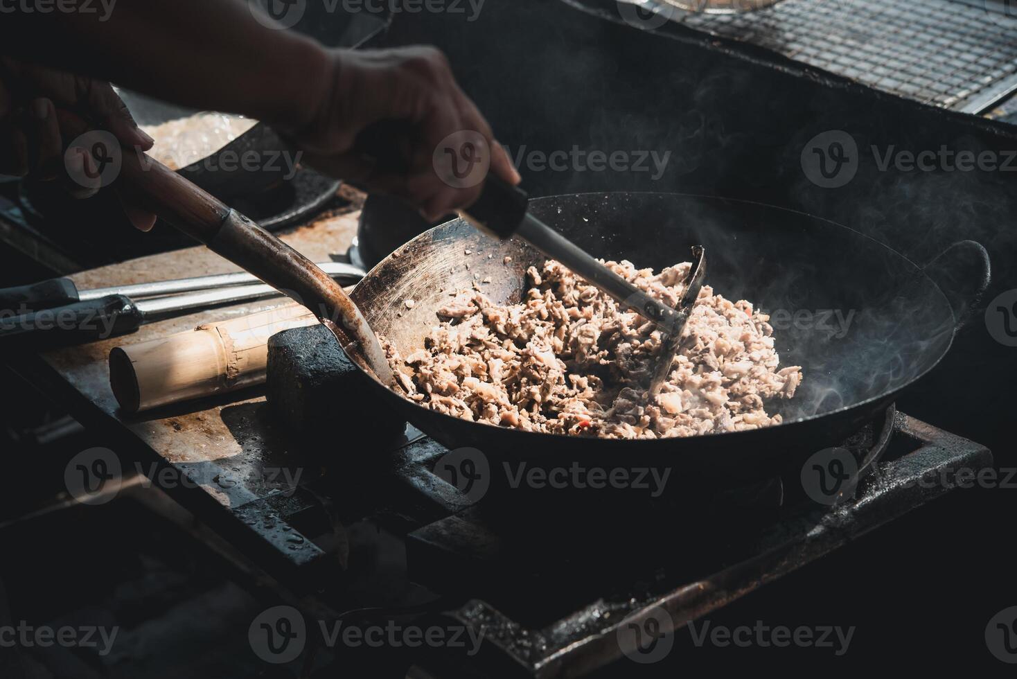 A person stirring a pan with meat in it photo