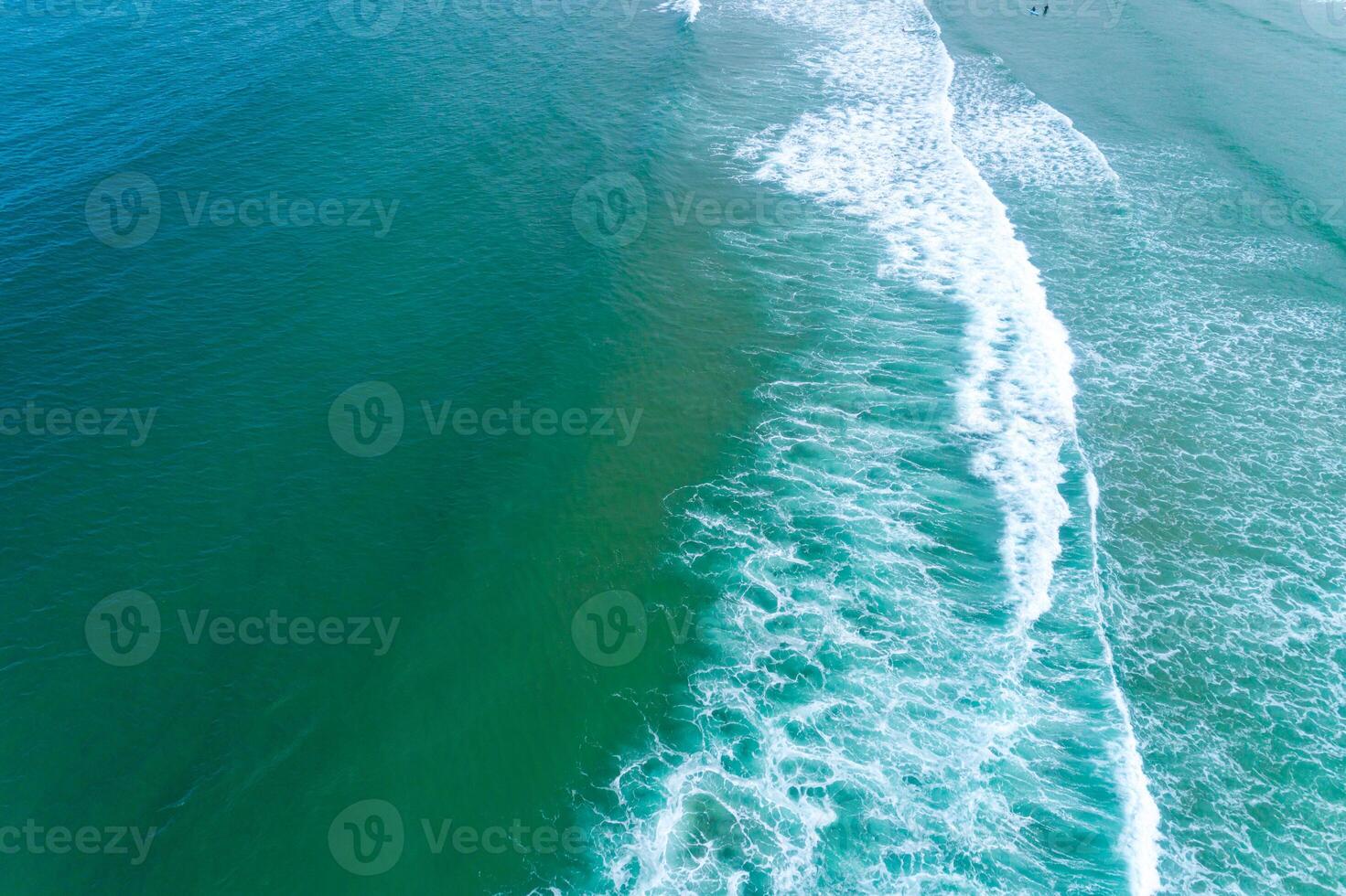overhead perspective of a tranquil ocean with a single breaking wave and subtle human presence photo