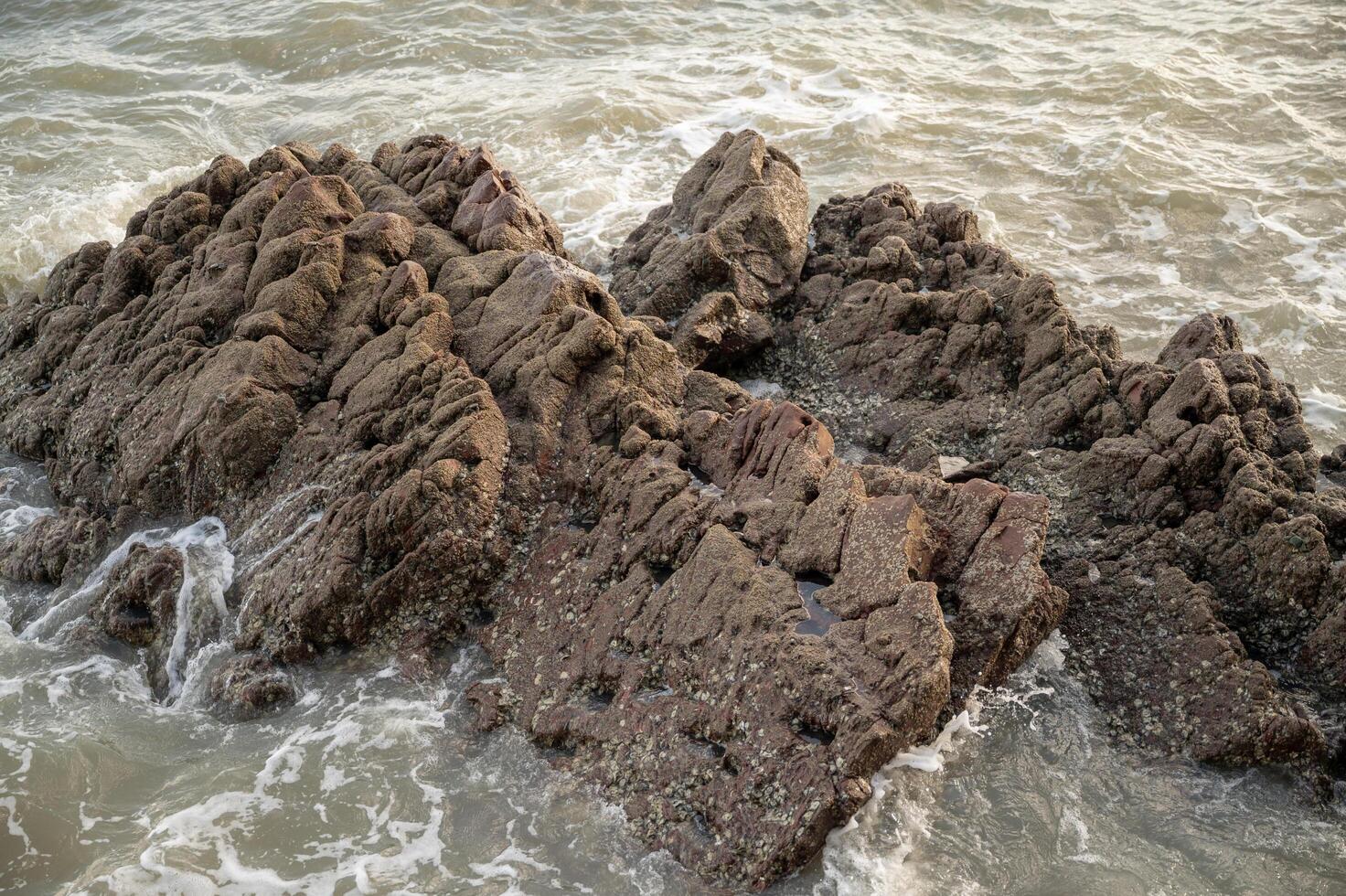 a large rock formation in the ocean with waves photo
