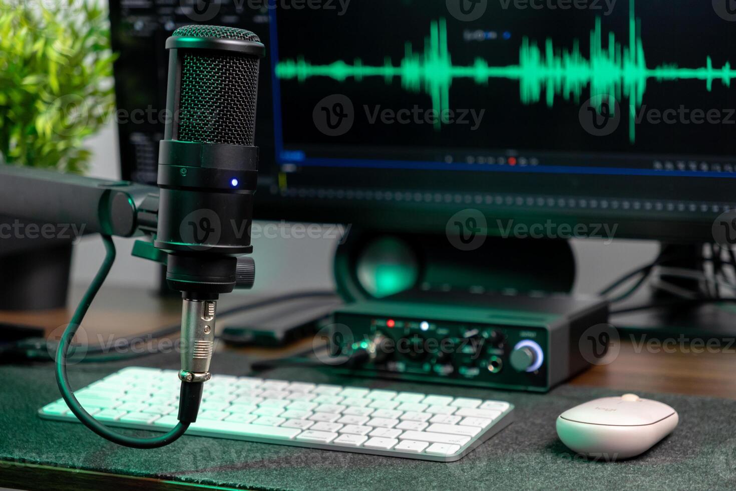 Black studio microphone on a desk with a computer monitor showing a green audio waveform, perfect for podcasting, music production, and content creation photo