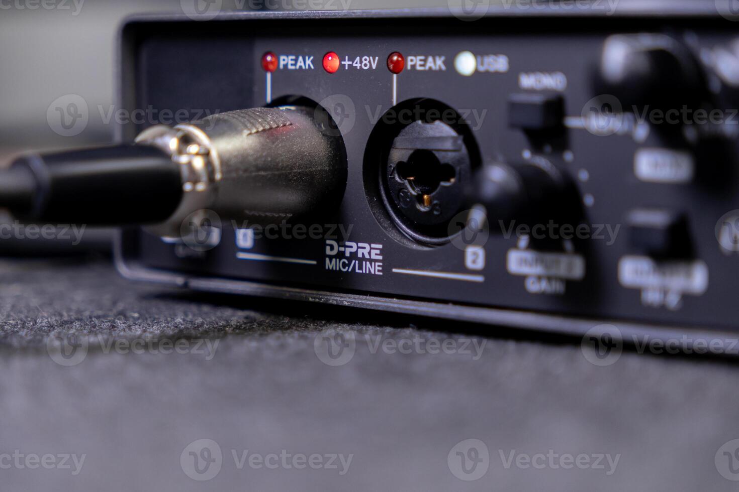 Audio interface closeup with XLR cable connected, showing MICLINE input, active PEAK and 48V indicators for professional sound recording photo