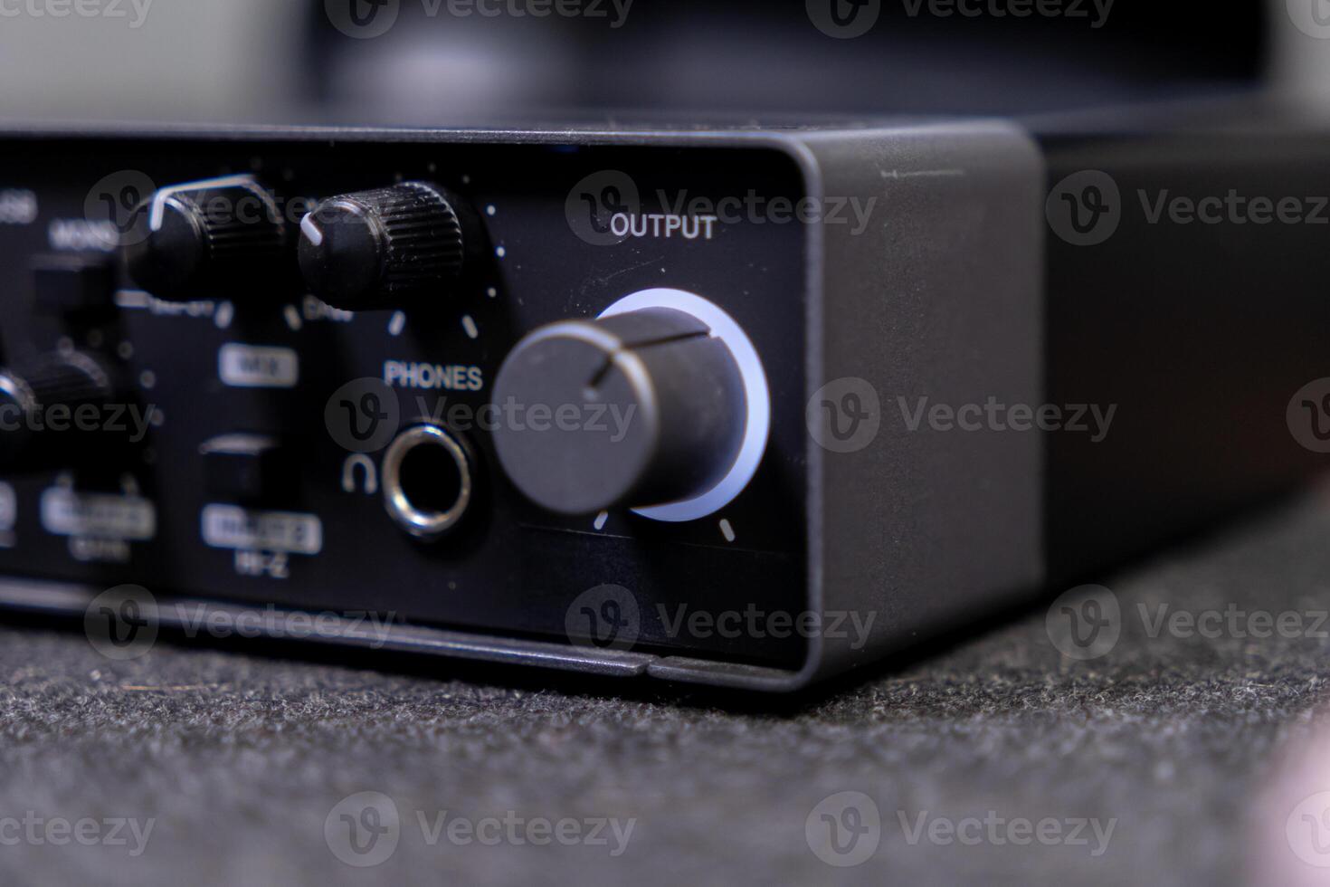 Close-up of a black audio interface showing output and phones controls, crucial equipment for professional music production and home studio recording setups photo