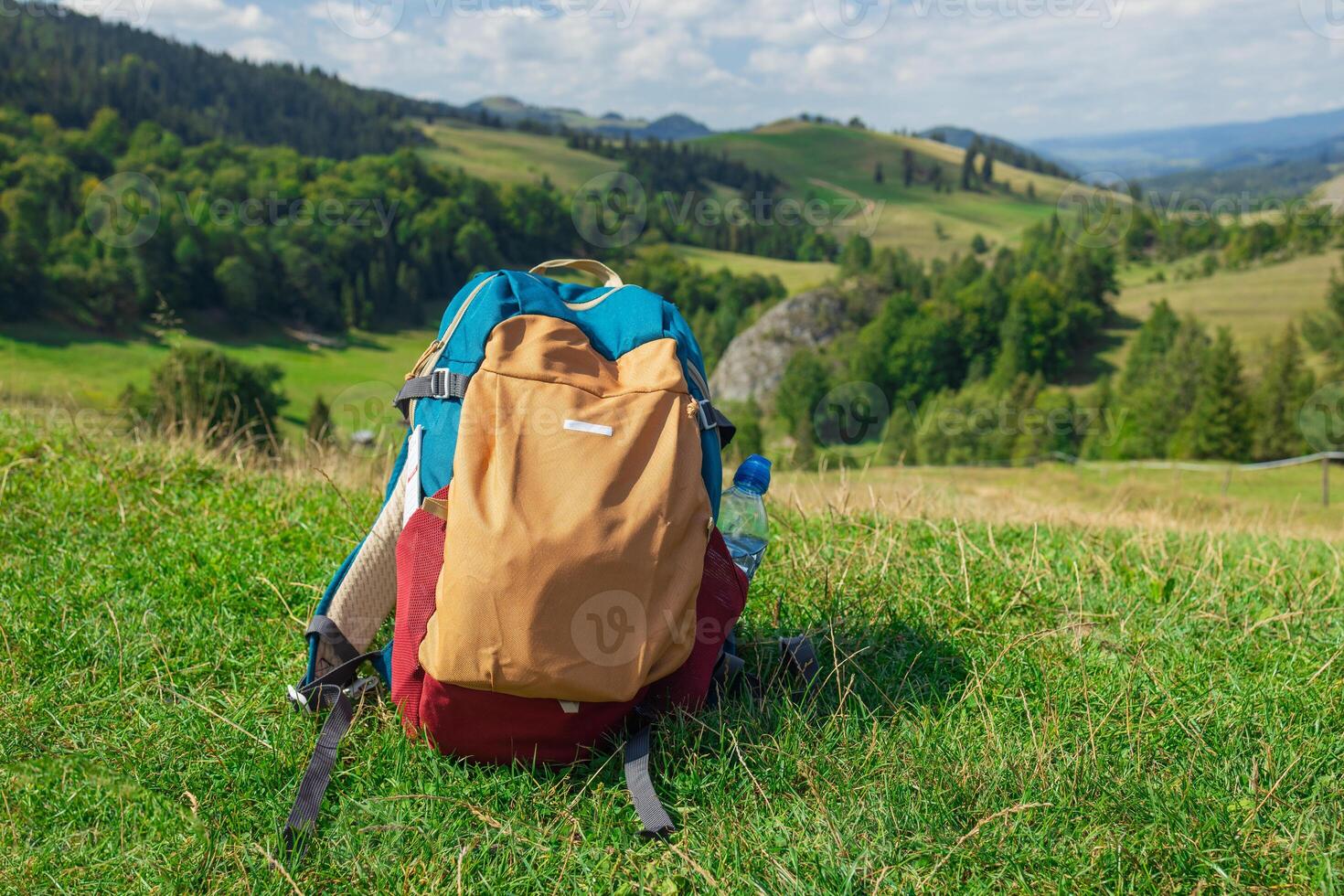 Backpack on Grassy Hill Overlooking Mountain Landscape photo