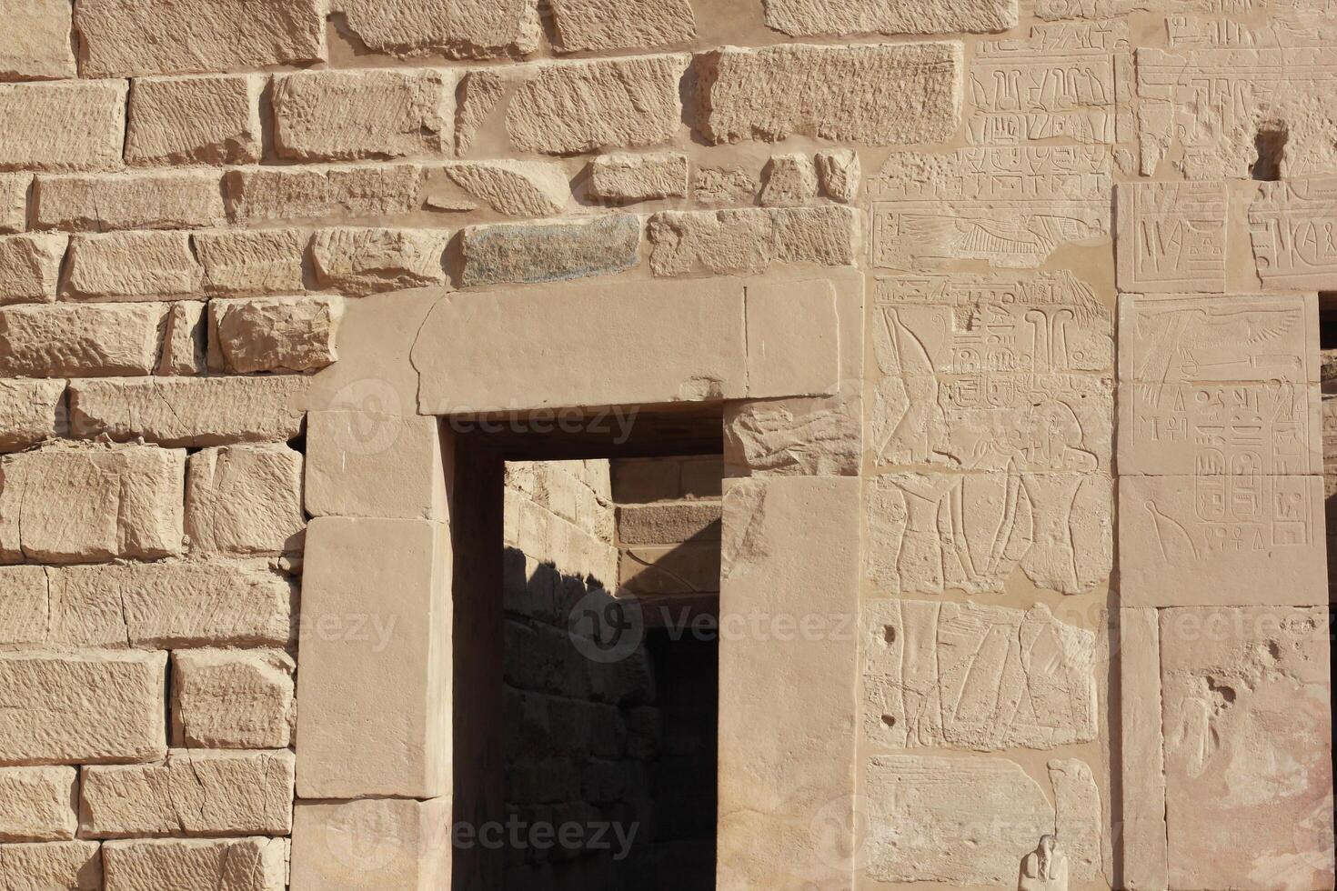 Ancient egyptian stone wall with carvings and open doorway. Egyptian drawings on the wall of Karnak temple in Luxor, Egypt. photo