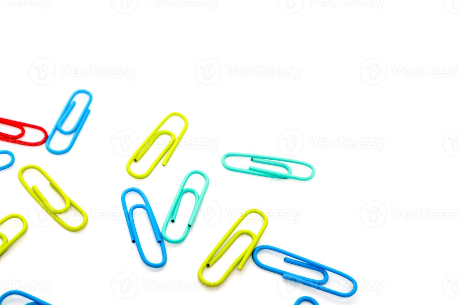 Colorful paper clips on white background, scattered stationery items in vibrant hues photo