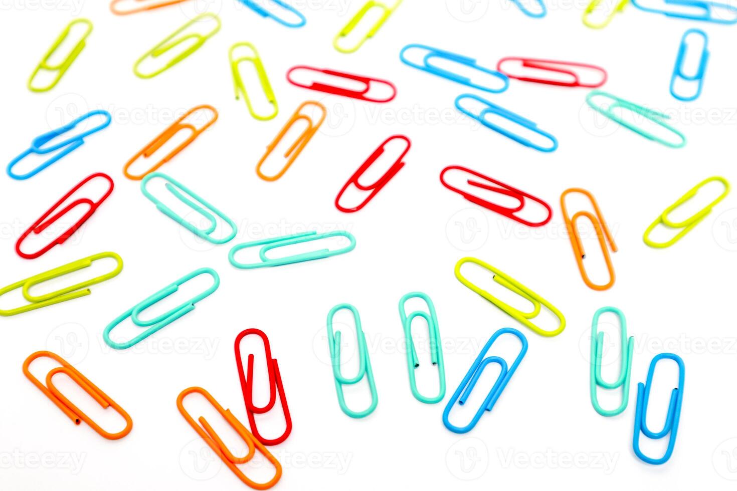 Vibrant Array of Colorful Paper Clips Scattered on a Clean White Surface Creating a Dynamic Composition photo