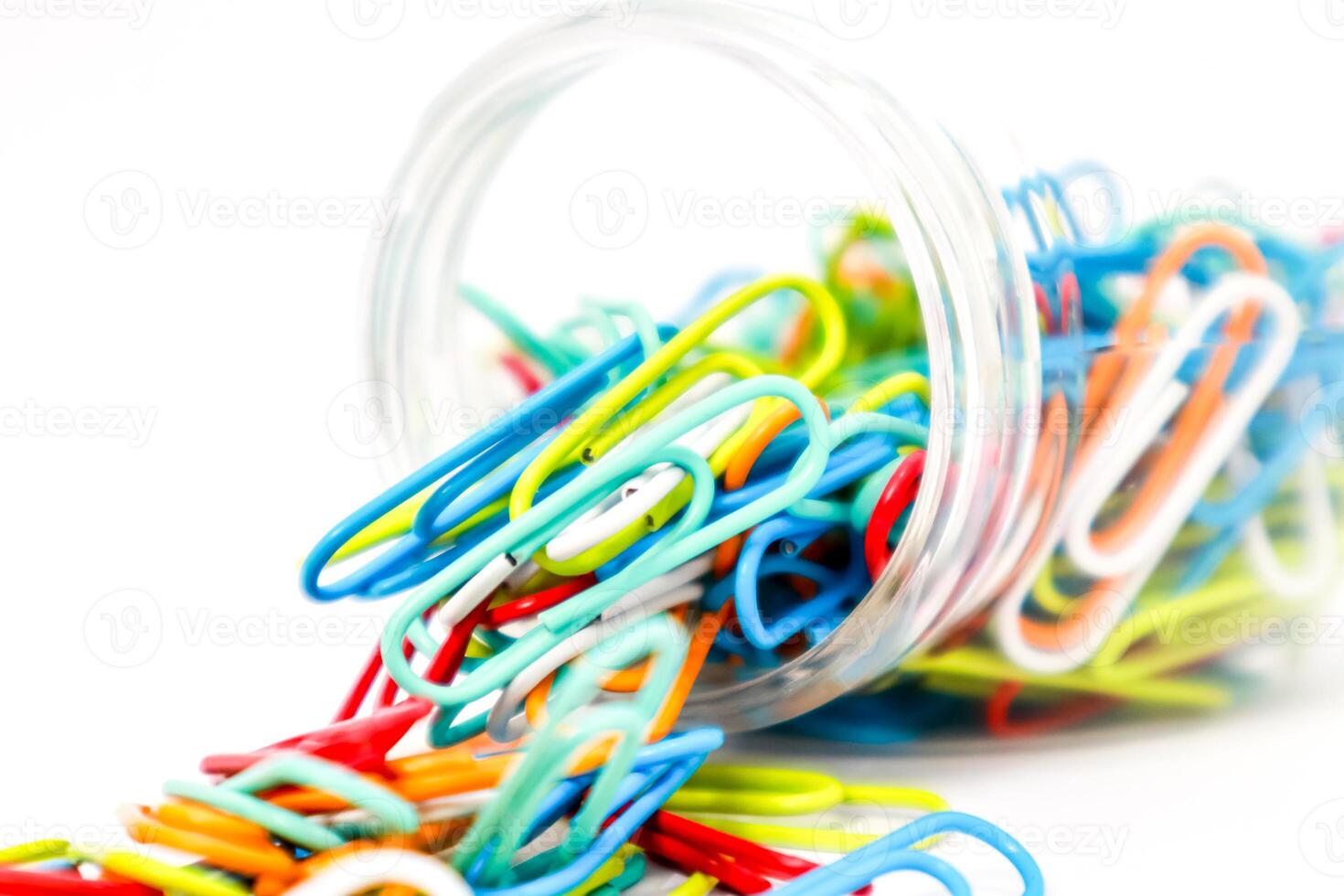Colorful Paper Clips Spill from a Tilted Glass Jar, Isolated on White photo