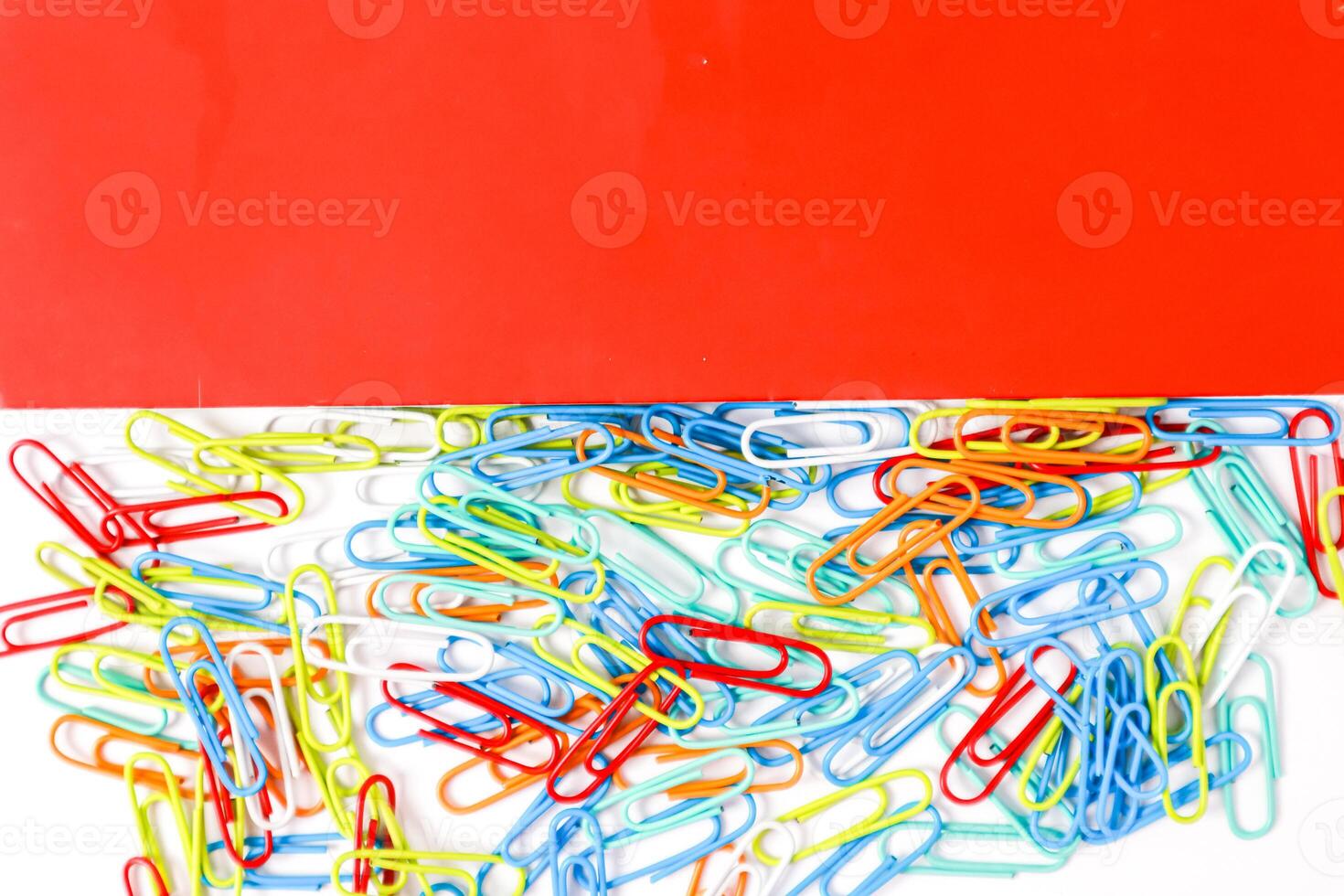 A Colorful Collection of Paper Clips Against a Red Background photo