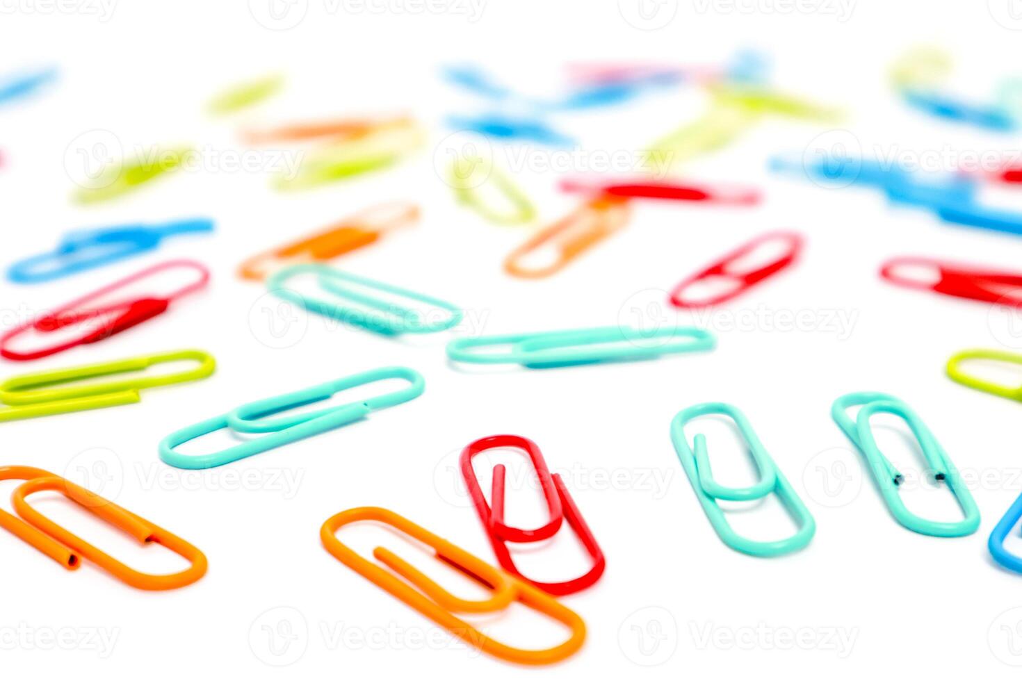 Scattered colorful paper clips on a white surface creating a vibrant pattern and a sense of disorganization or creativity photo