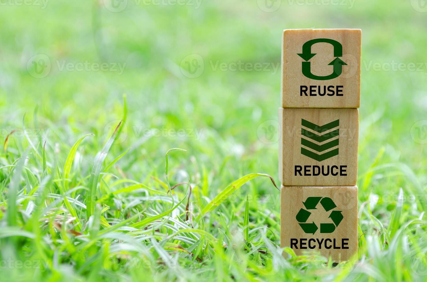 Wooden cube stack with text that reads recycle, reuse and reduce icons on green grass. Environmental concept. photo