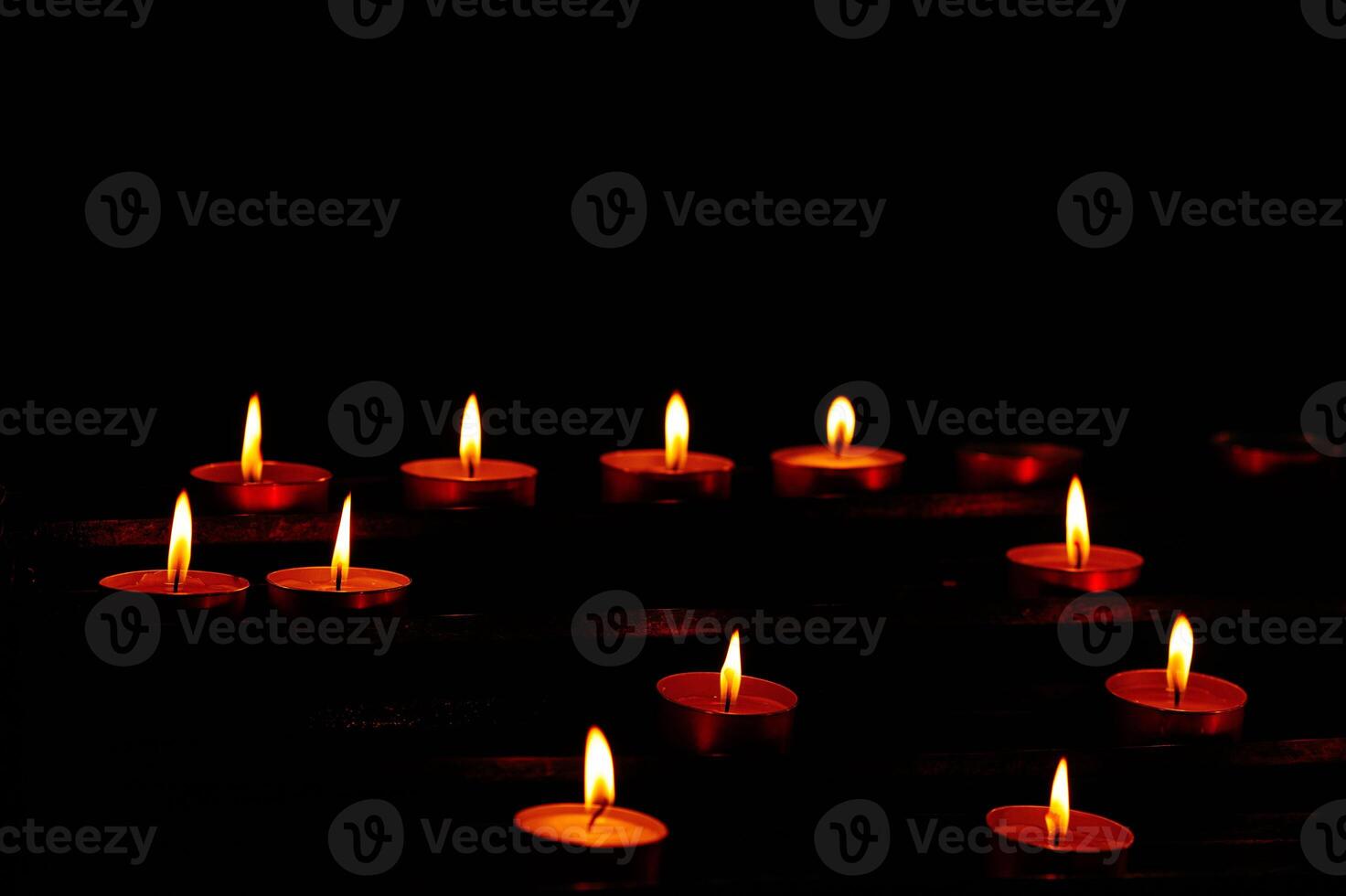 Illuminated red tealight candles against dark background photo