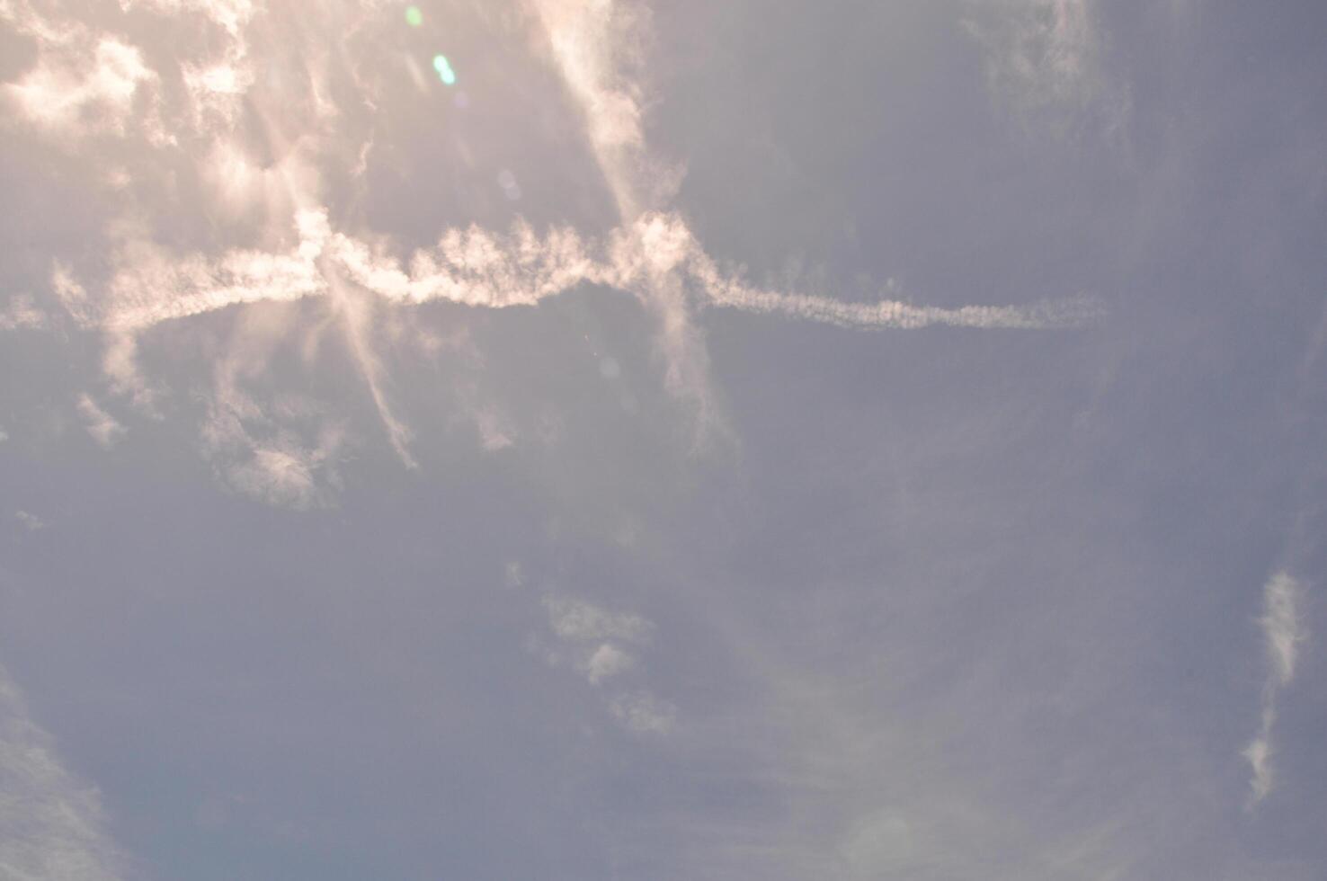 Sun-kissed sky streaked with ethereal clouds and lingering contrails, painting a dynamic atmospheric canvas. photo