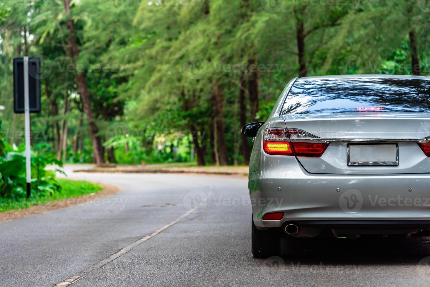 Rear view of car going on the green forest road with break light, car travel and transportation concept. photo