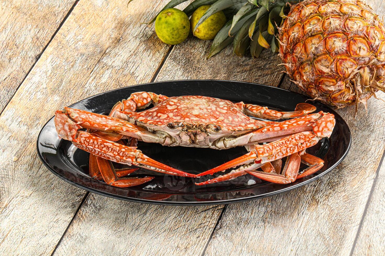 A crab on a plate with a pineapple and a pineapple on a table photo