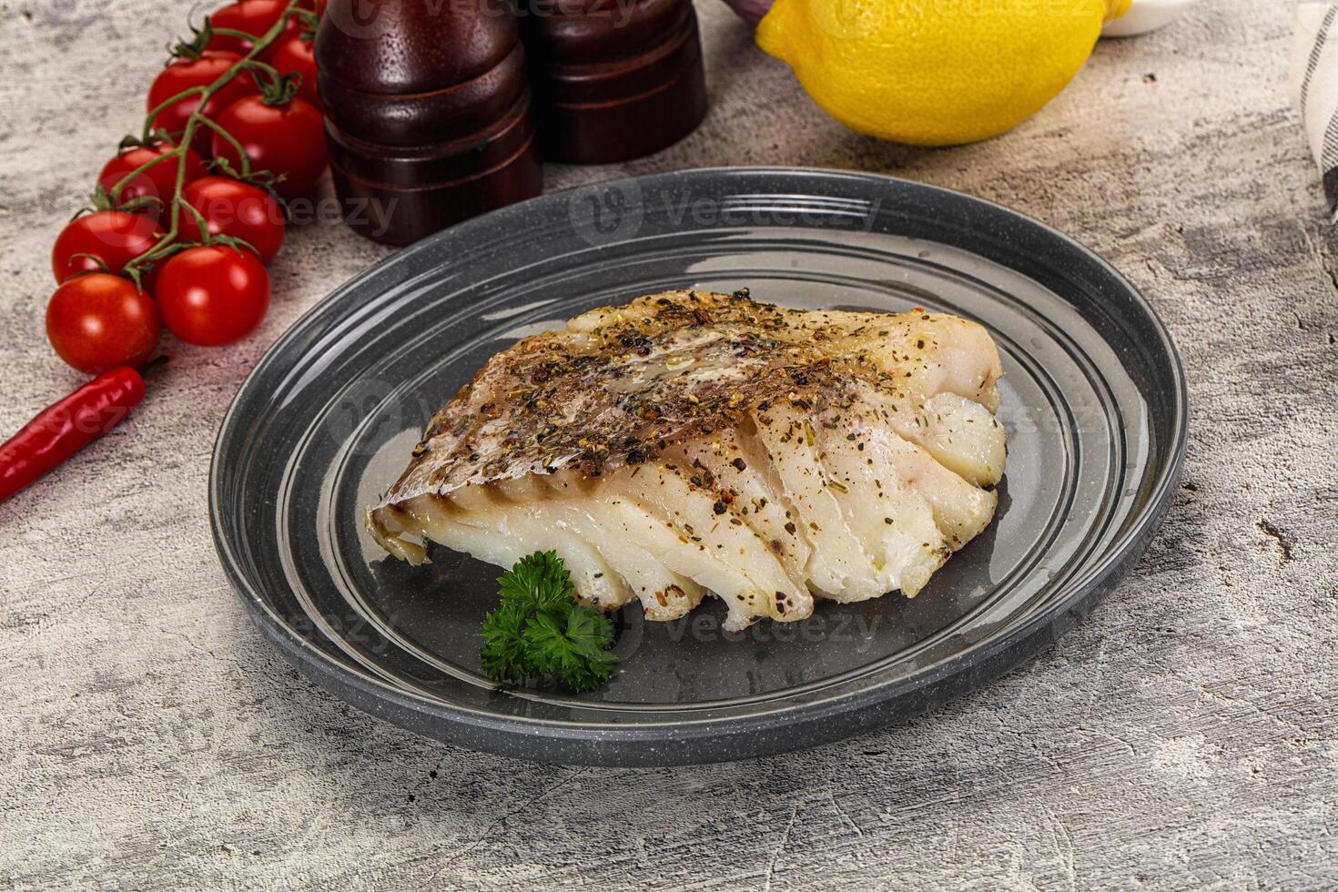 A plate of fish on a table next to a bottle of lemon juice photo