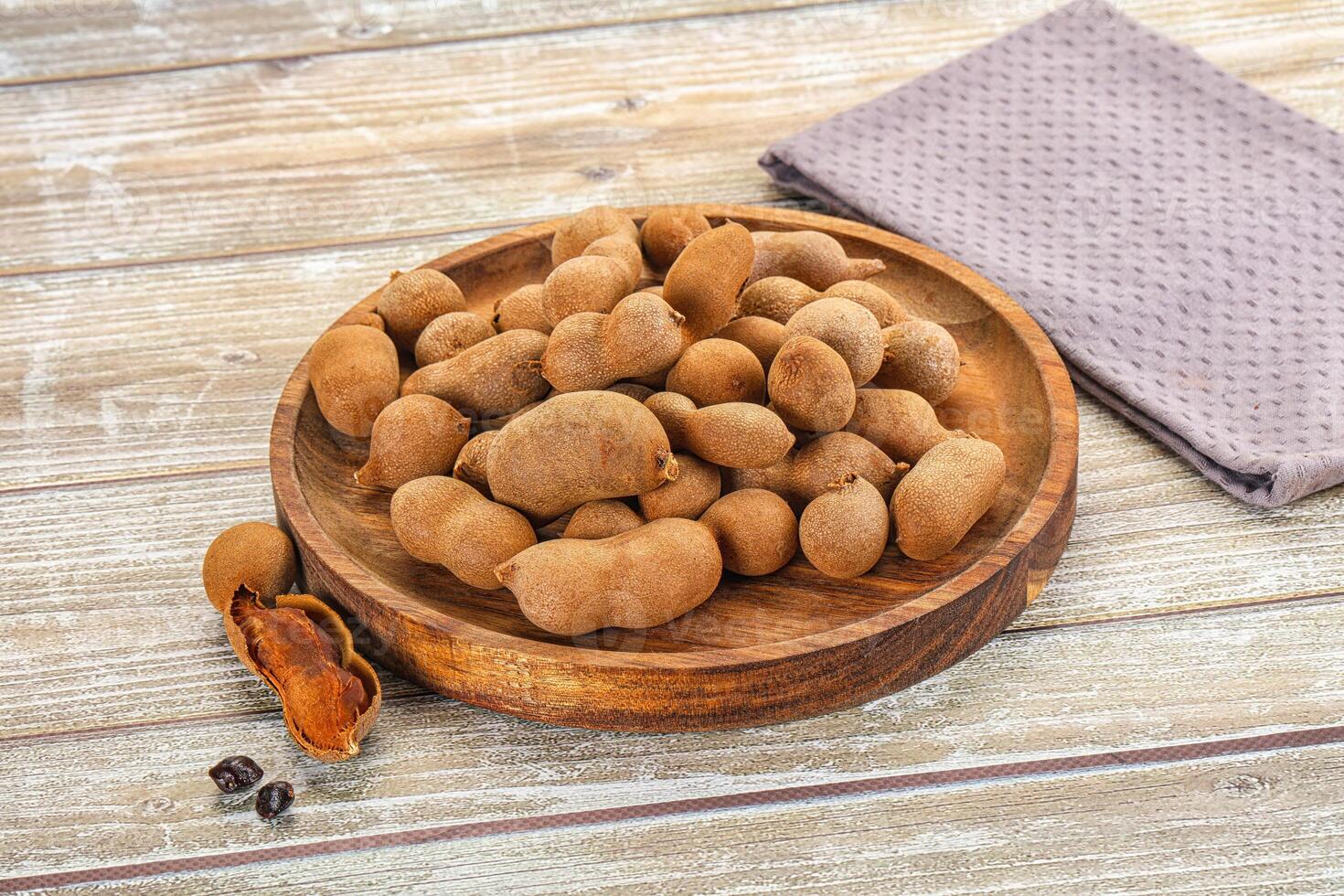 A wooden bowl filled with nuts on a wooden table photo