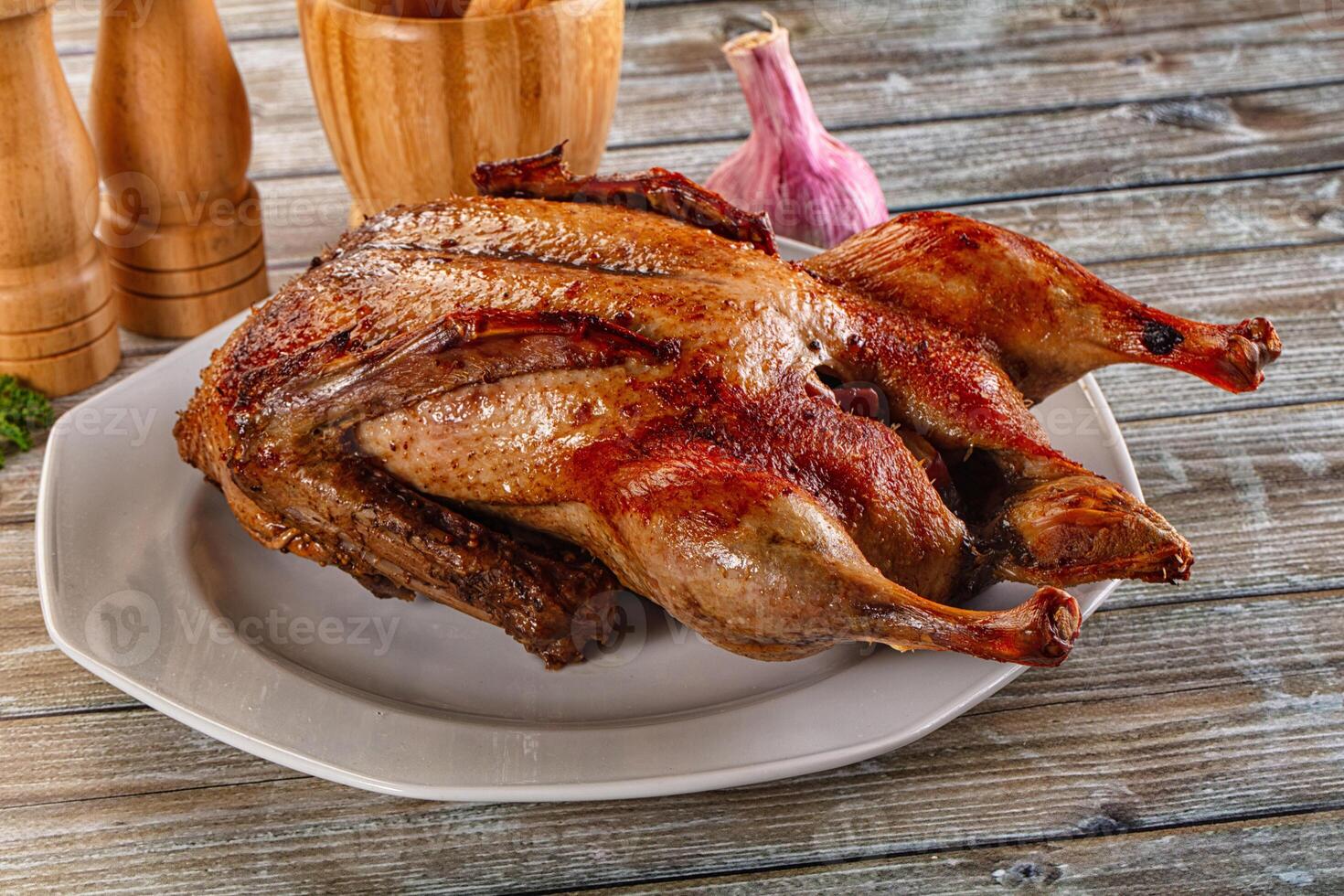 A roasted chicken on a plate with garlic and spices photo