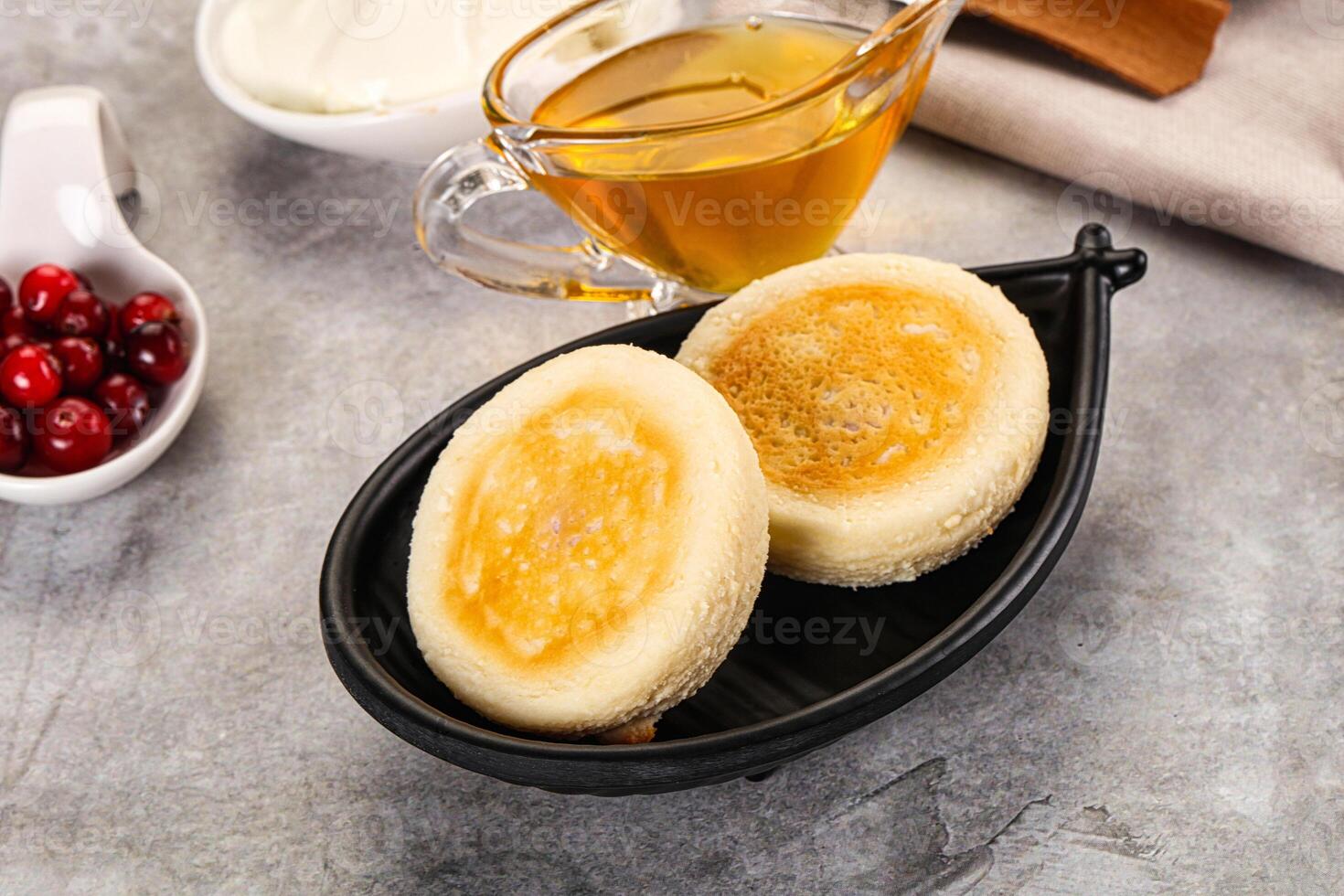 Two pancakes sit in a black dish with butter and cranberries photo