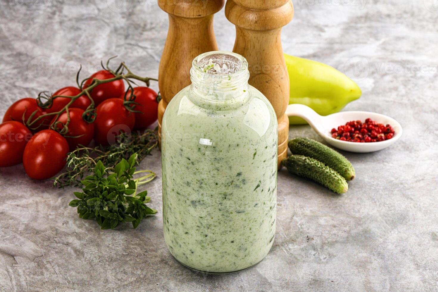 A bottle of dressing sitting next to a pepper and a tomato photo
