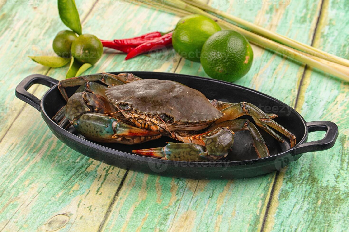 A crab is sitting in a black dish on a wooden table photo
