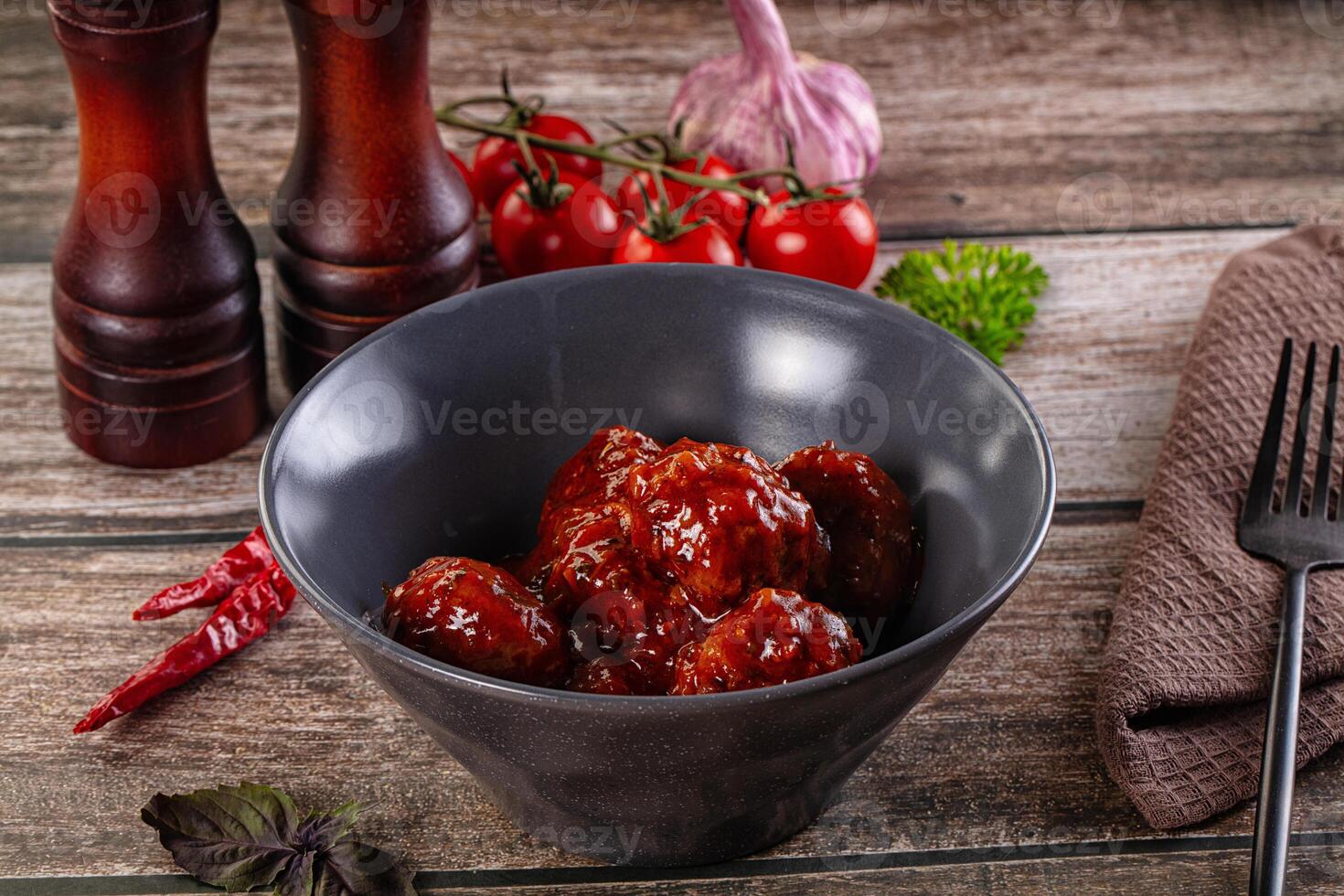 A bowl of meatballs sitting on a table next to a knife and fork photo