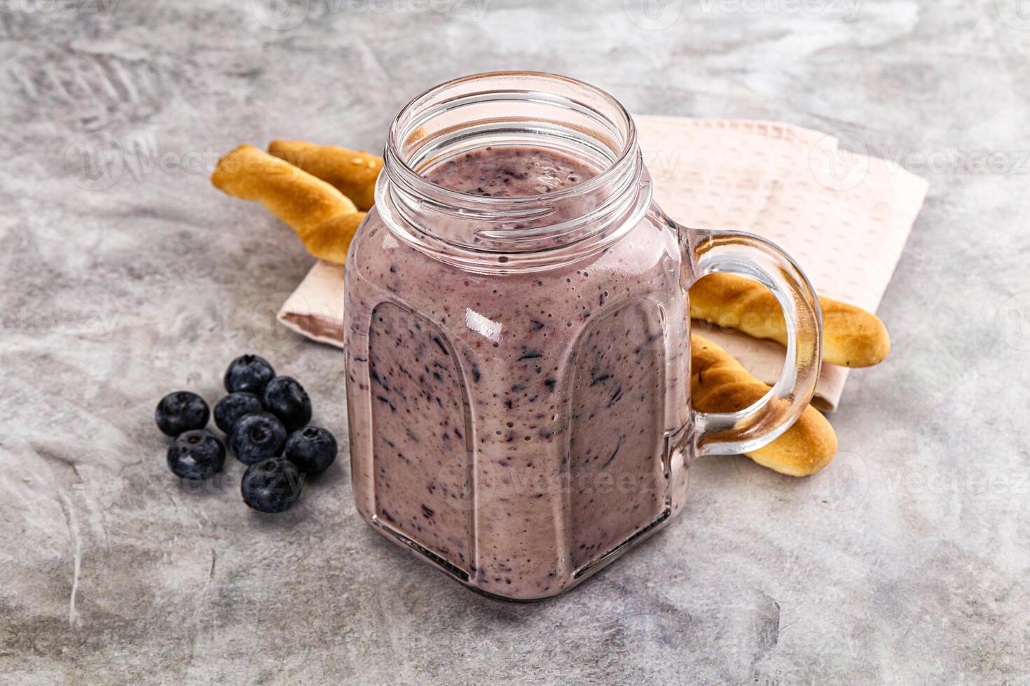 A glass jar with blueberry smoothie and a spoon photo