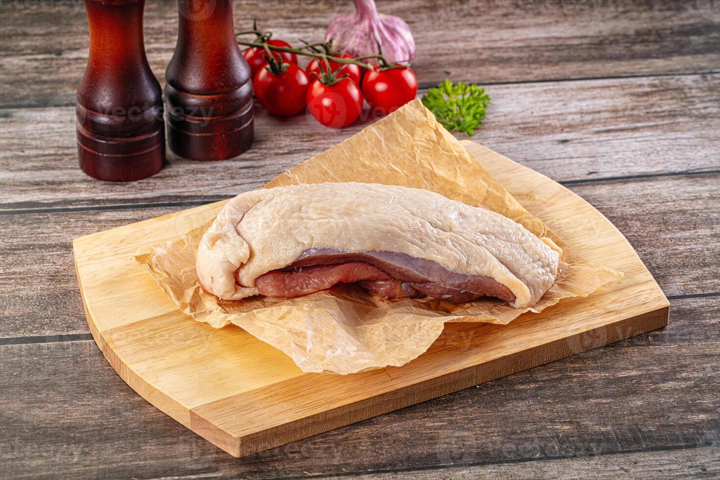 A piece of meat on a cutting board with a bottle of ketchup and a bottle of vinegar photo