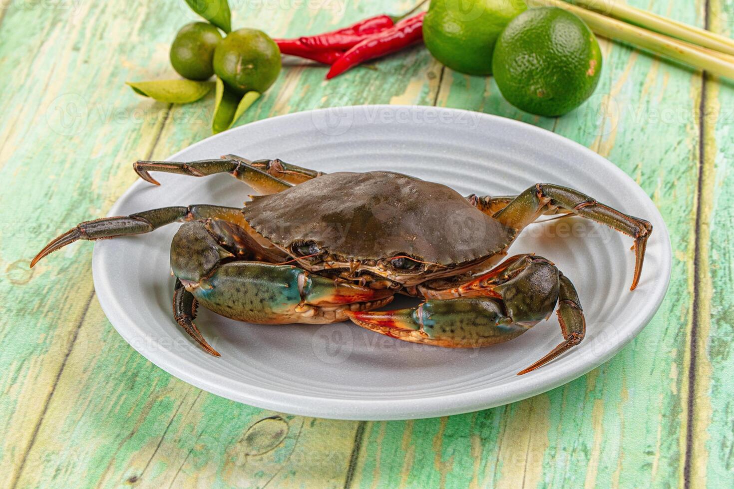A crab on a plate with some limes and other ingredients photo