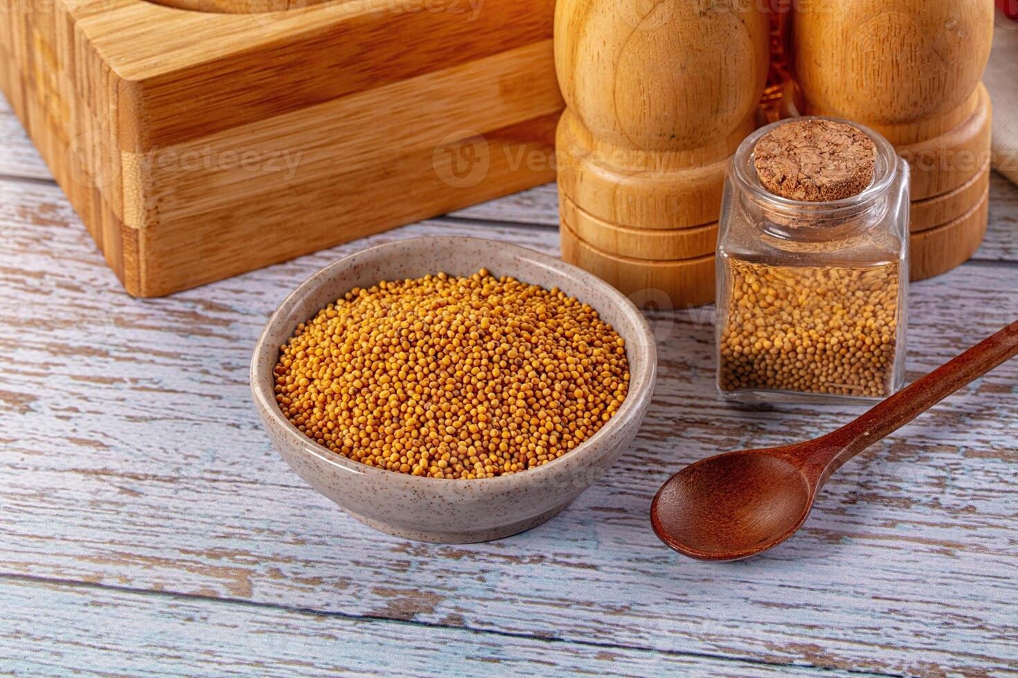 A wooden table with a bowl of mustard and spices photo