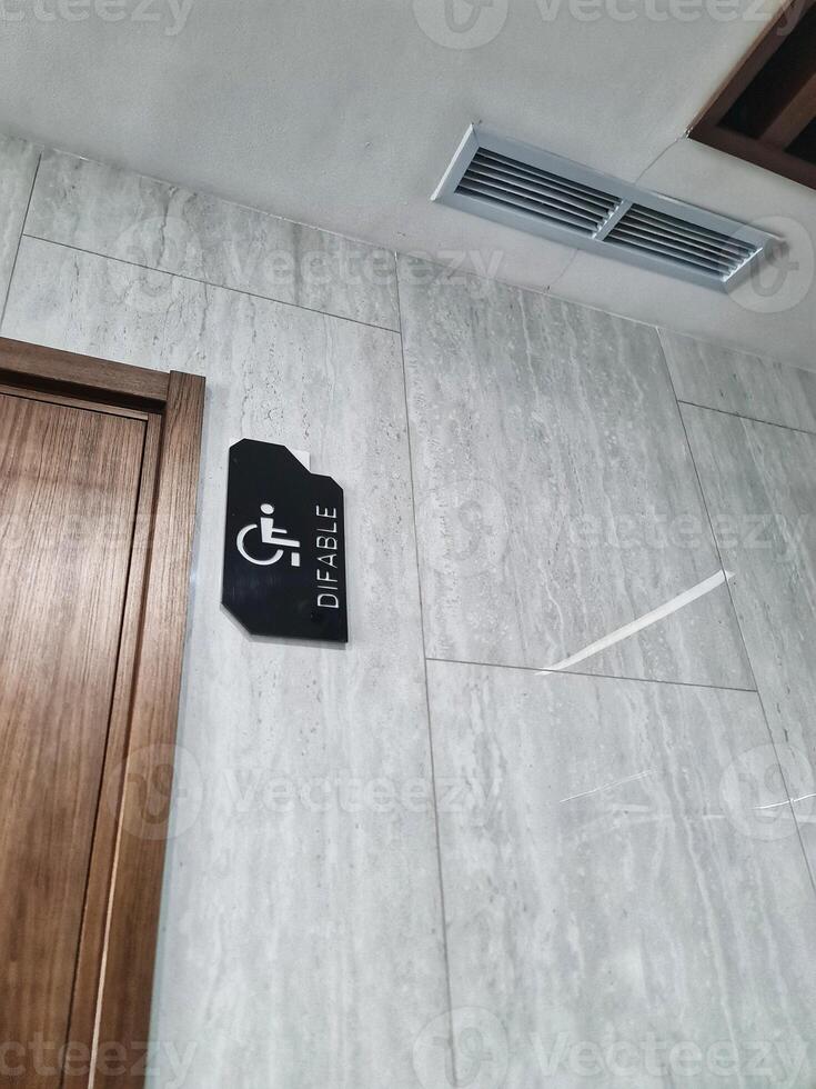 Bathroom Accessibility with Wheelchair Sign on Marble Wall Near Wooden Door photo