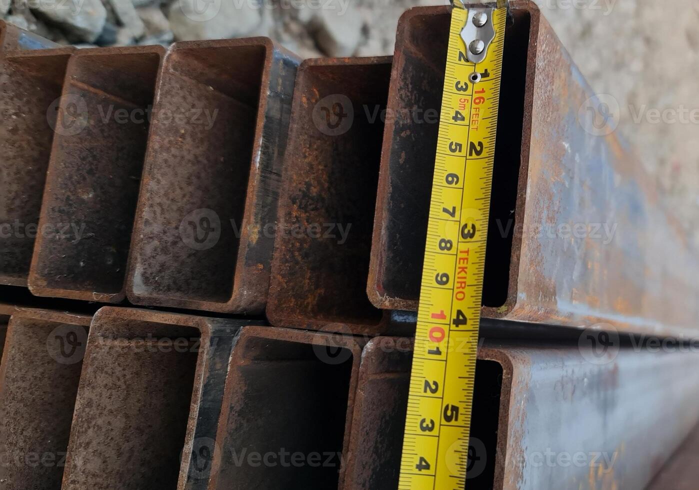 Measuring Rusty Steel U-channel Beams with Tape Measure for Construction photo
