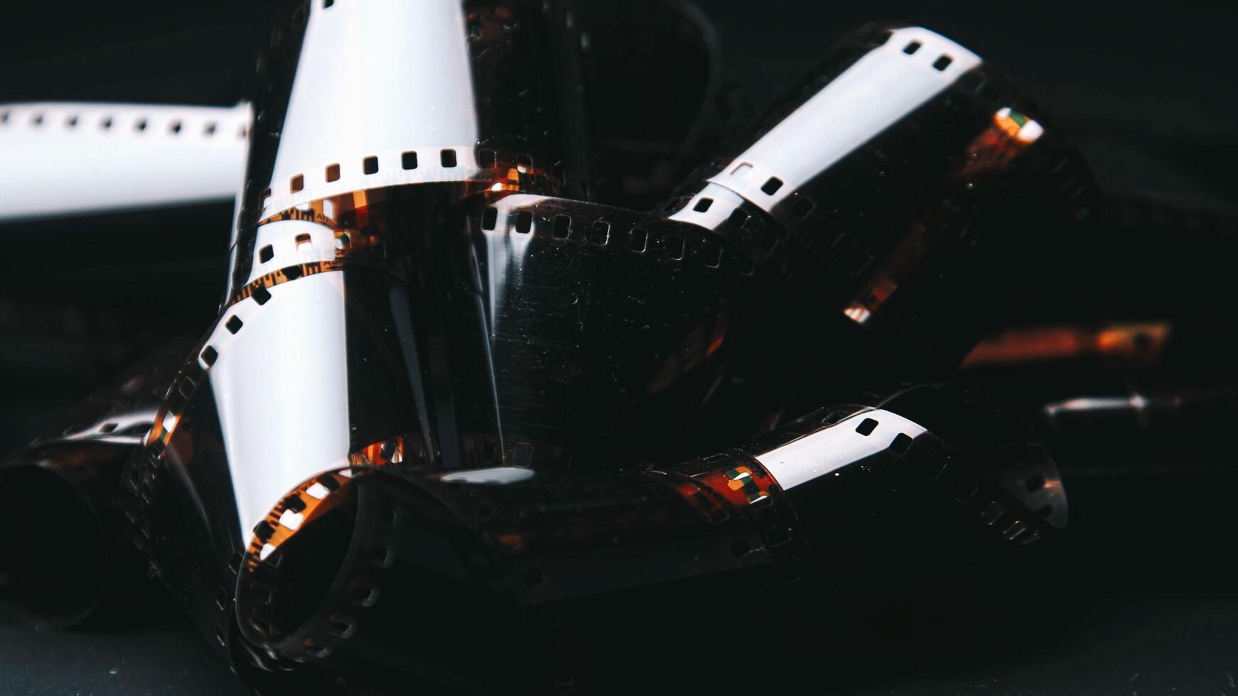 The film is aged, with faded colors. An old, rolled up color film lies on a dark background, symbolizing the memories imprinted on it. photo