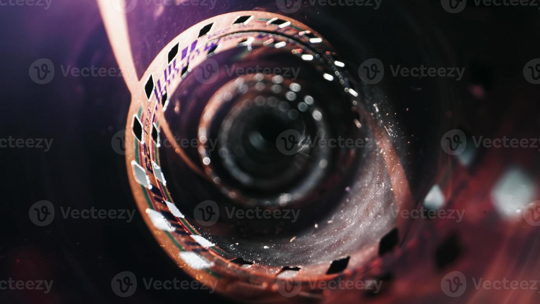 Close-up of a film reel, featuring its perforations and smooth surface. Set against a dark background, it evokes a sense of vintage charm and nostalgia. photo