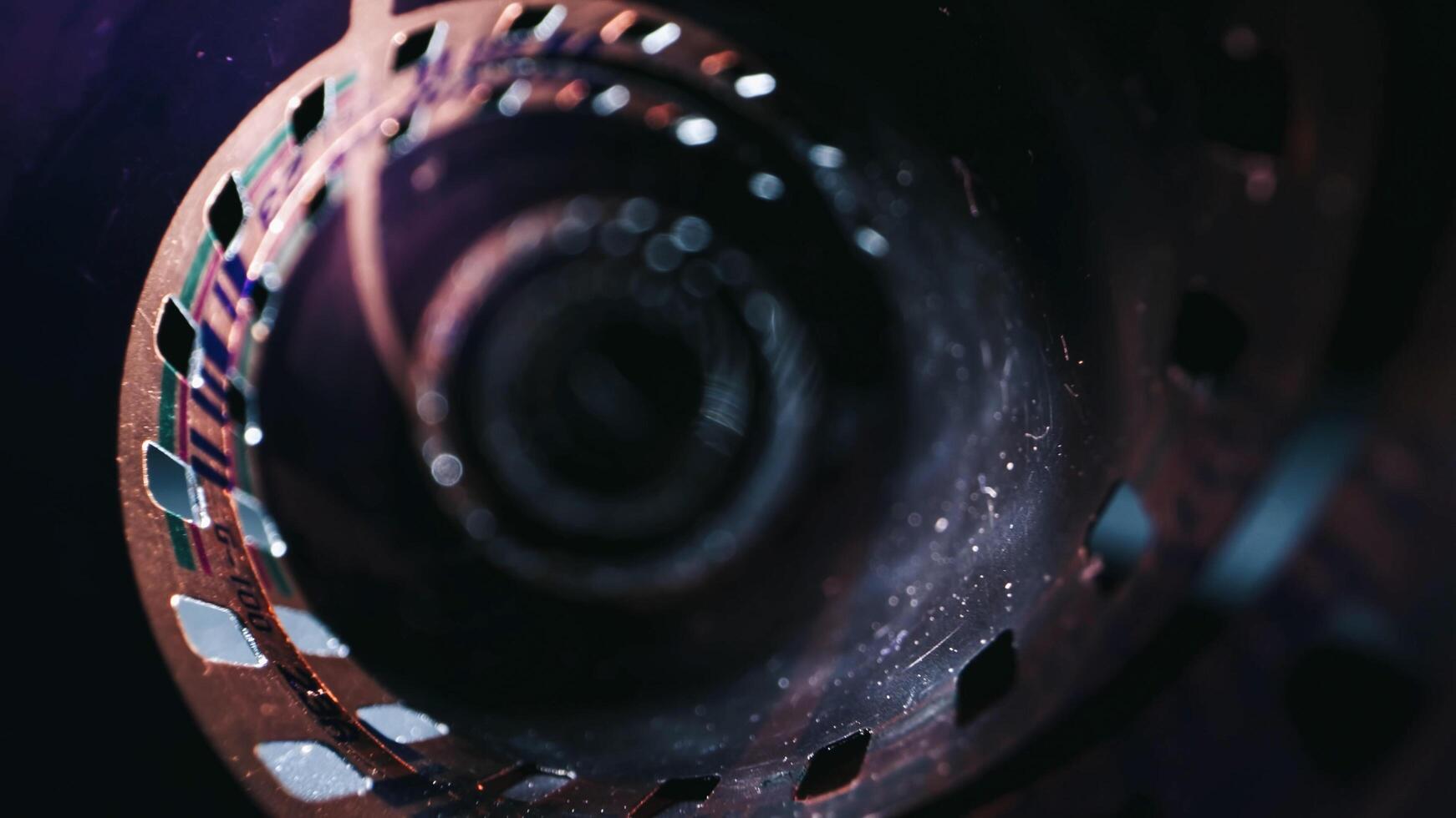 An old, rolled up color film lies on a dark background, symbolizing the memories captured on it. The film is aged, with faded colors in a retro style photo