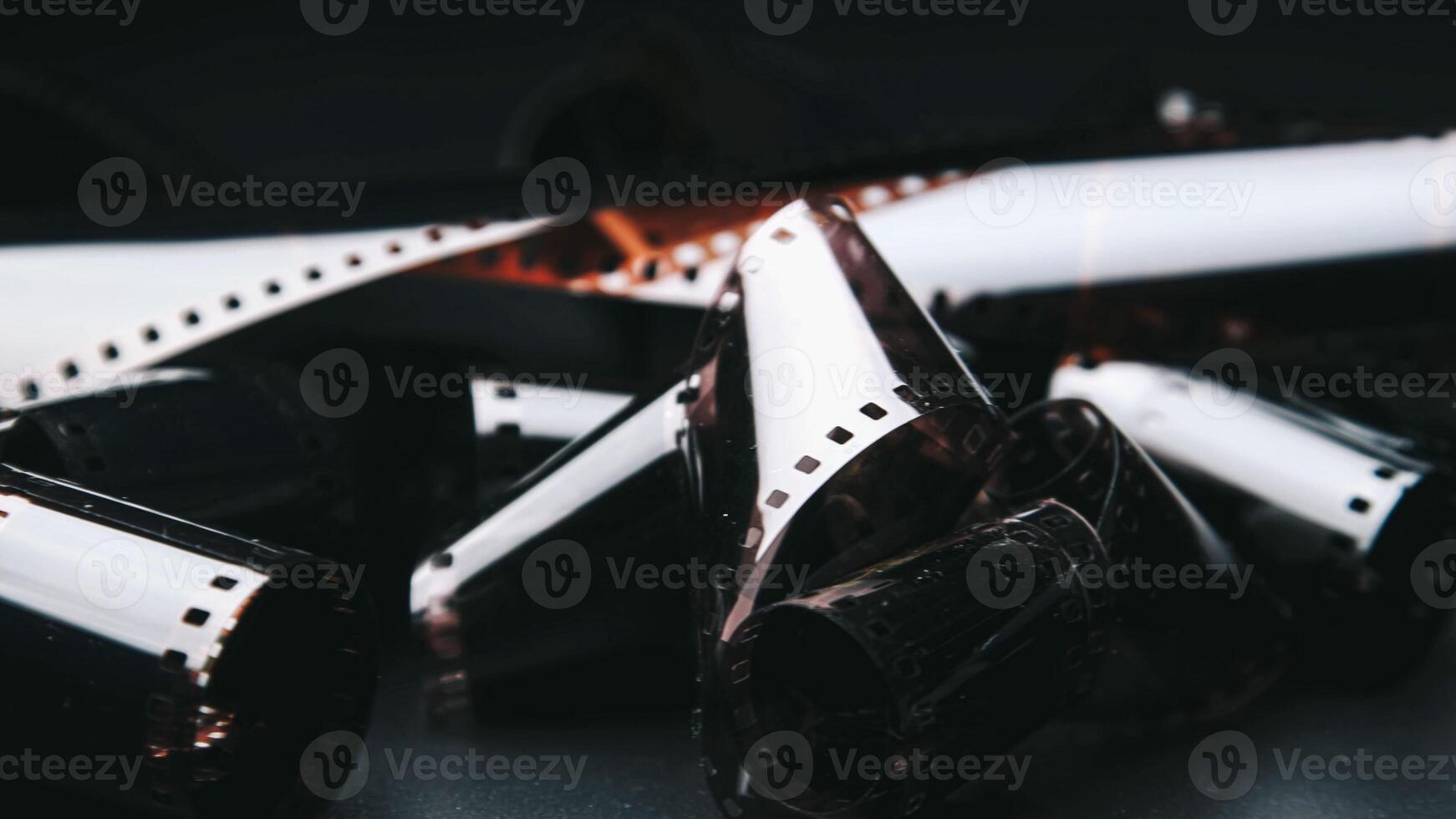 Photographic film isolated on a dark background, evoking a vintage and nostalgic feel. Close-up of a roll of film showing its perforated edges and smooth surface photo