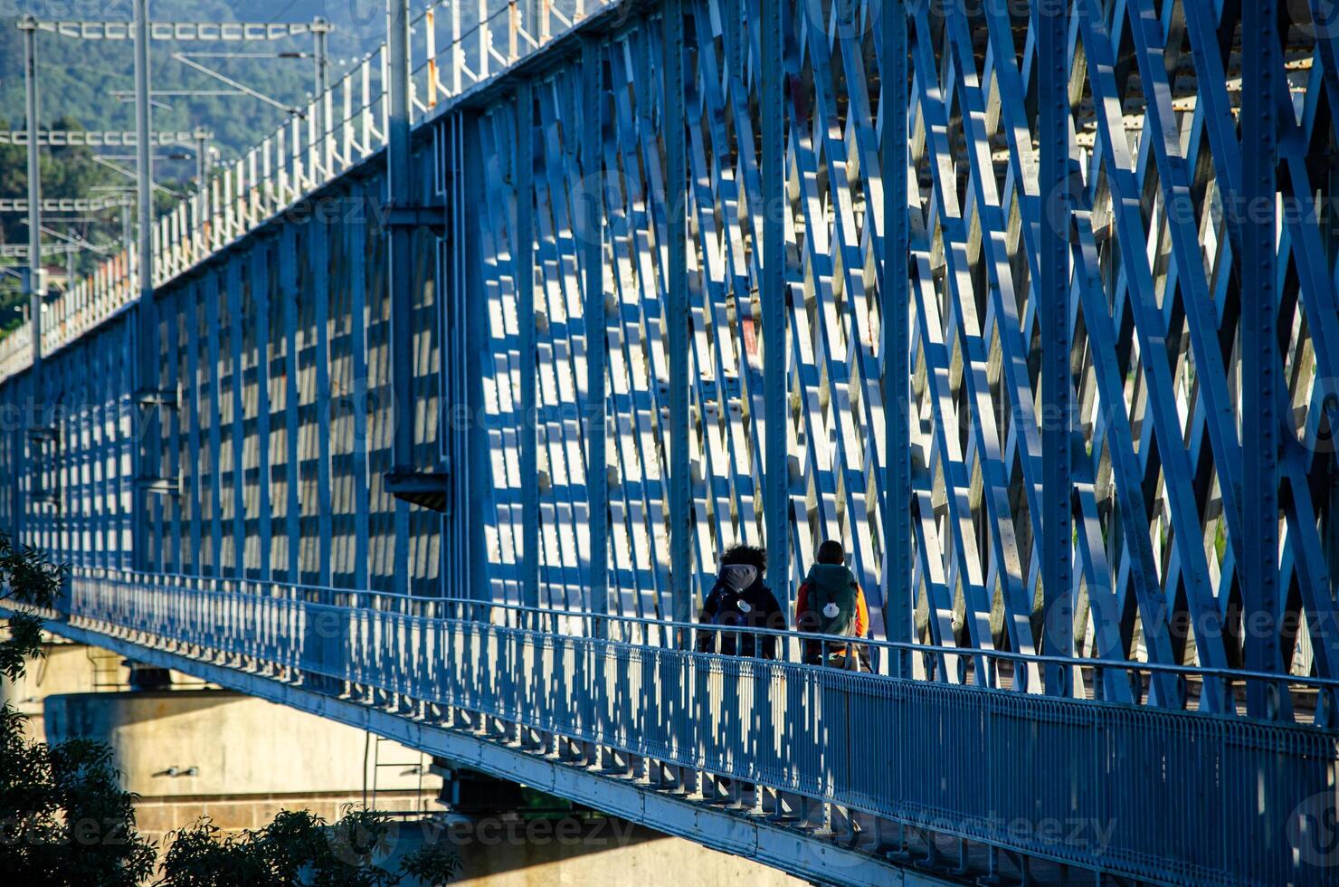 two pilgrims to Santiago de Compostela crossing the international bridge over the river Minho between Tui and Valenca do Minho from Portugal photo
