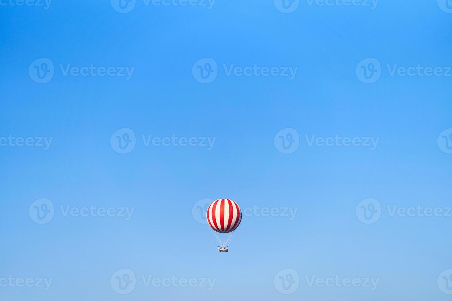 View of a red and white hot air balloon on a blue sky background photo