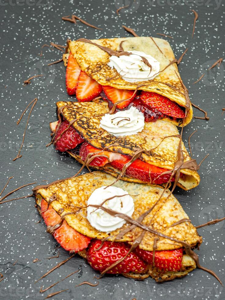 Three crepes with strawberries and whipped cream photo