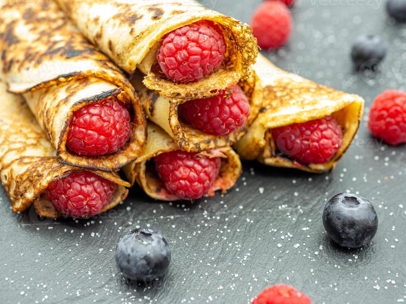 A pile of pancakes with raspberries and blueberries photo