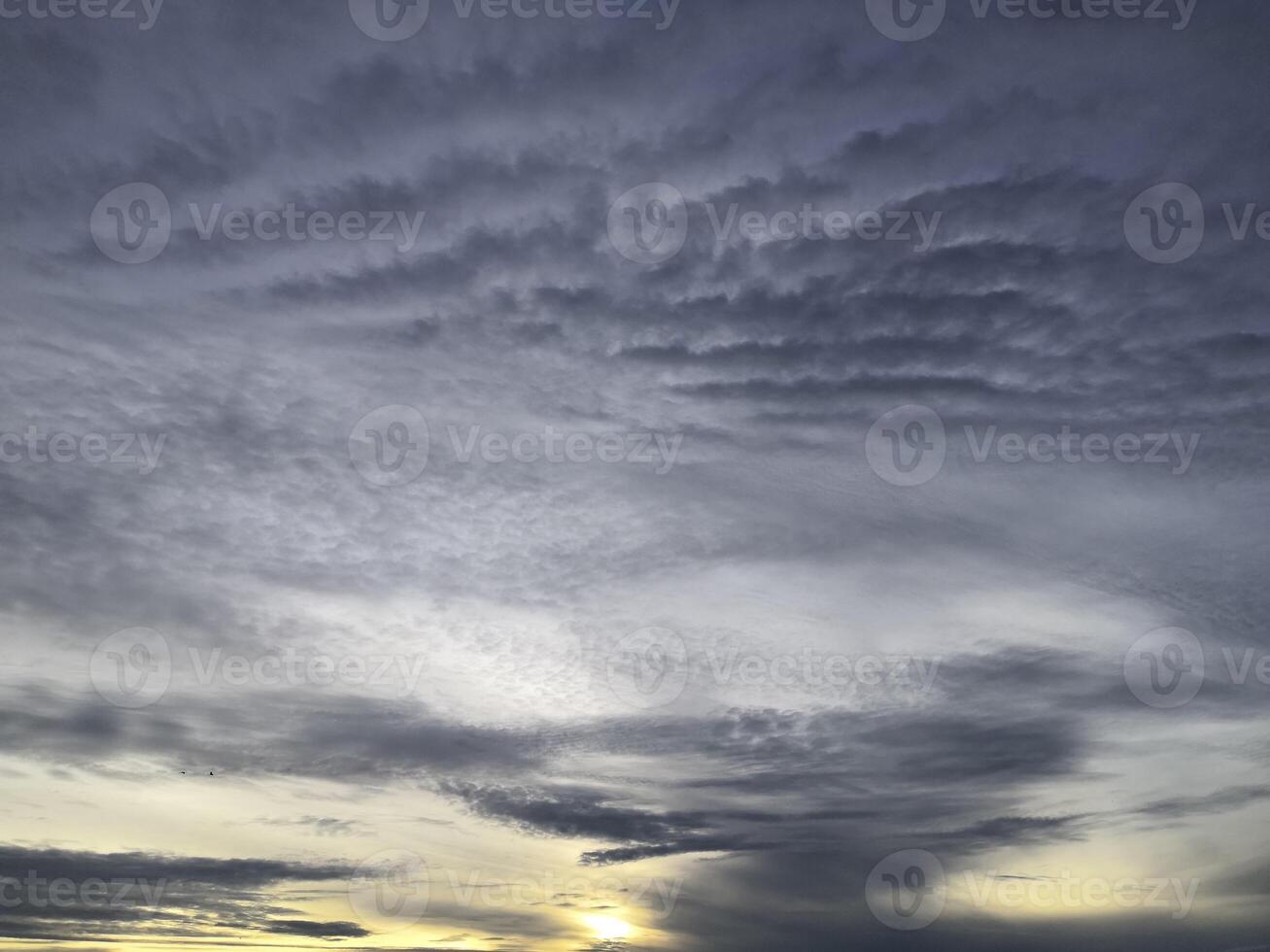 A sunset over the ocean with clouds in the sky photo
