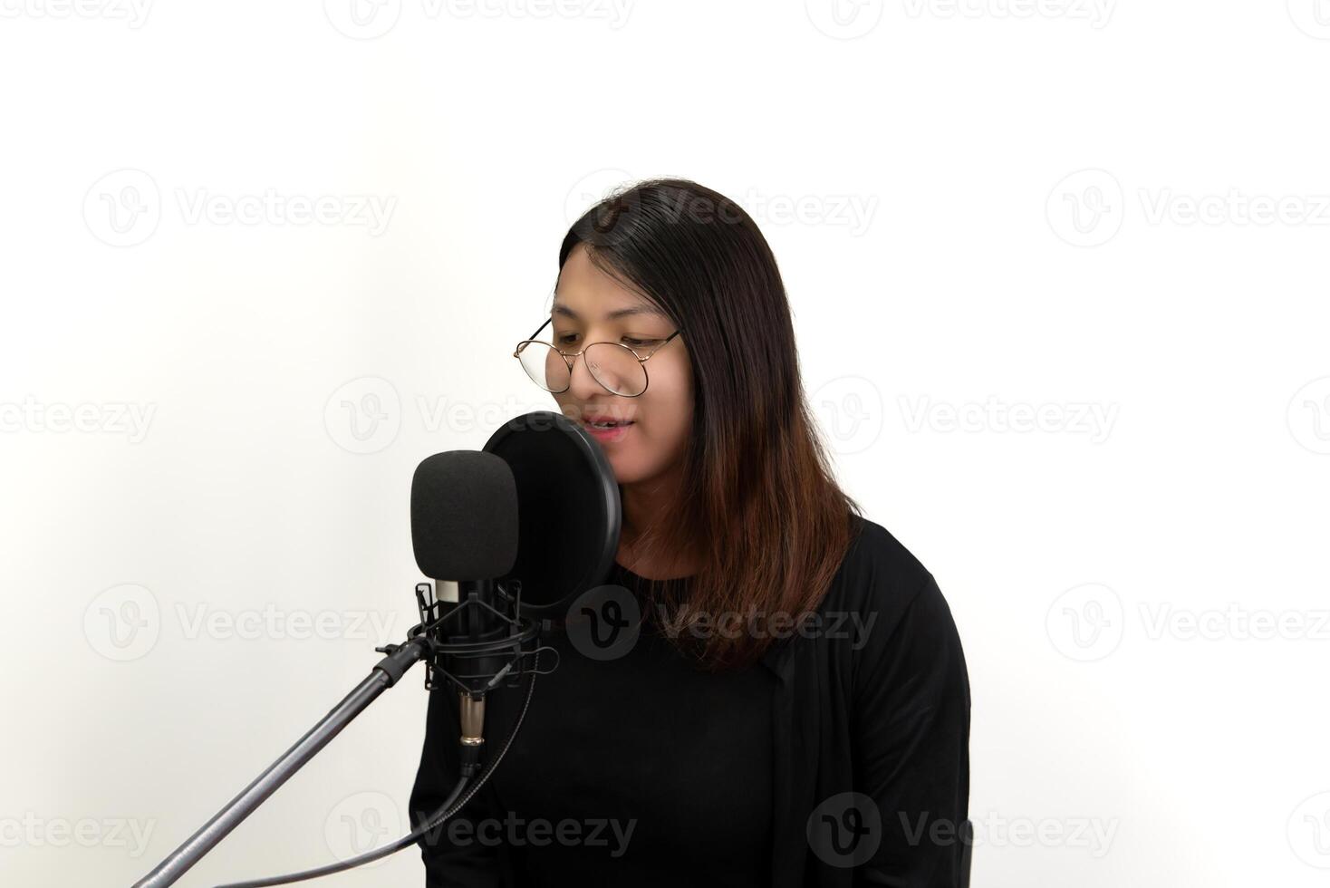 A woman singing into a microphone in front of a white background photo