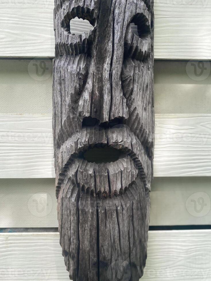 A wooden face mask with a beard on a wall photo