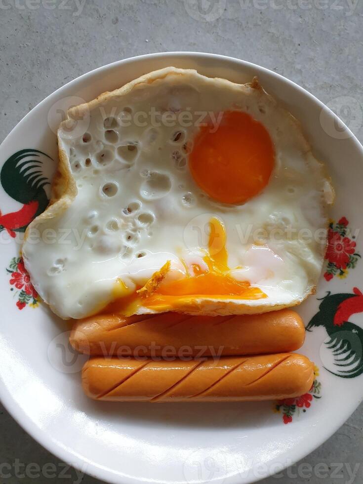 A plate with an egg, hot dog, and a fried egg photo