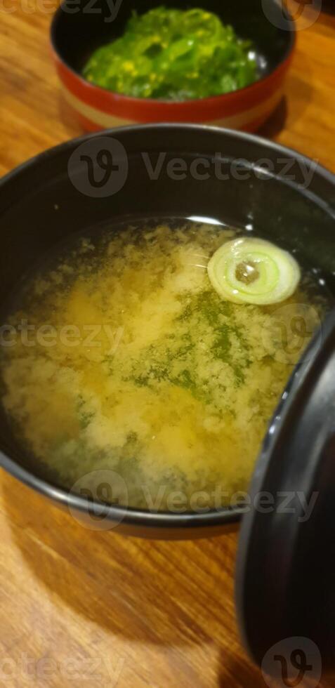 A bowl of soup with a green onion in it photo