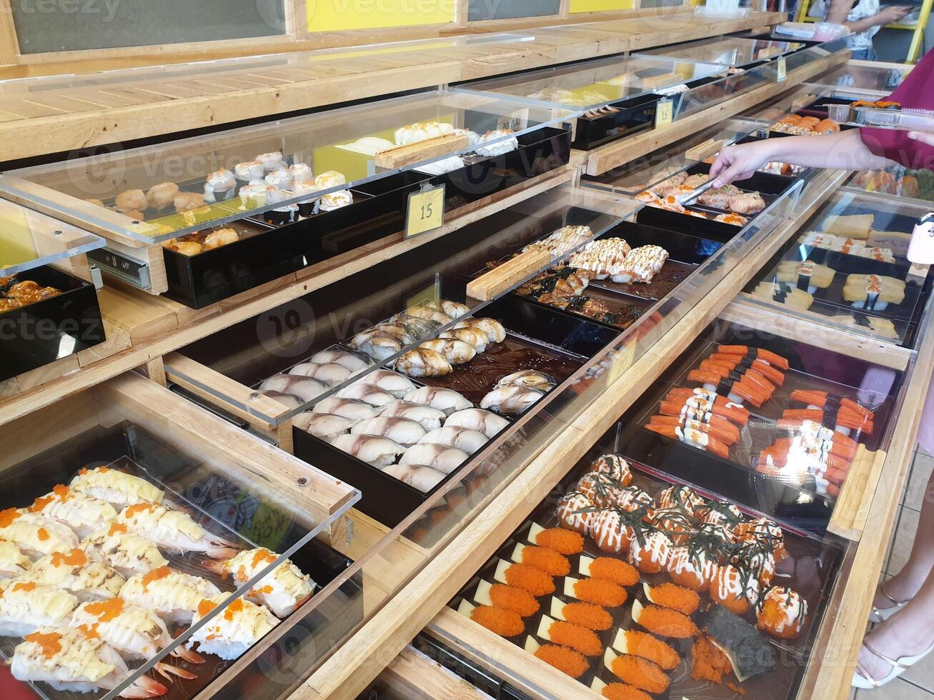 A woman is looking at a display of sushi photo