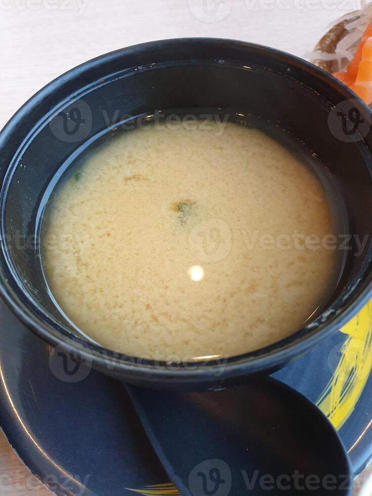 A bowl of soup with a spoon sitting on a table photo