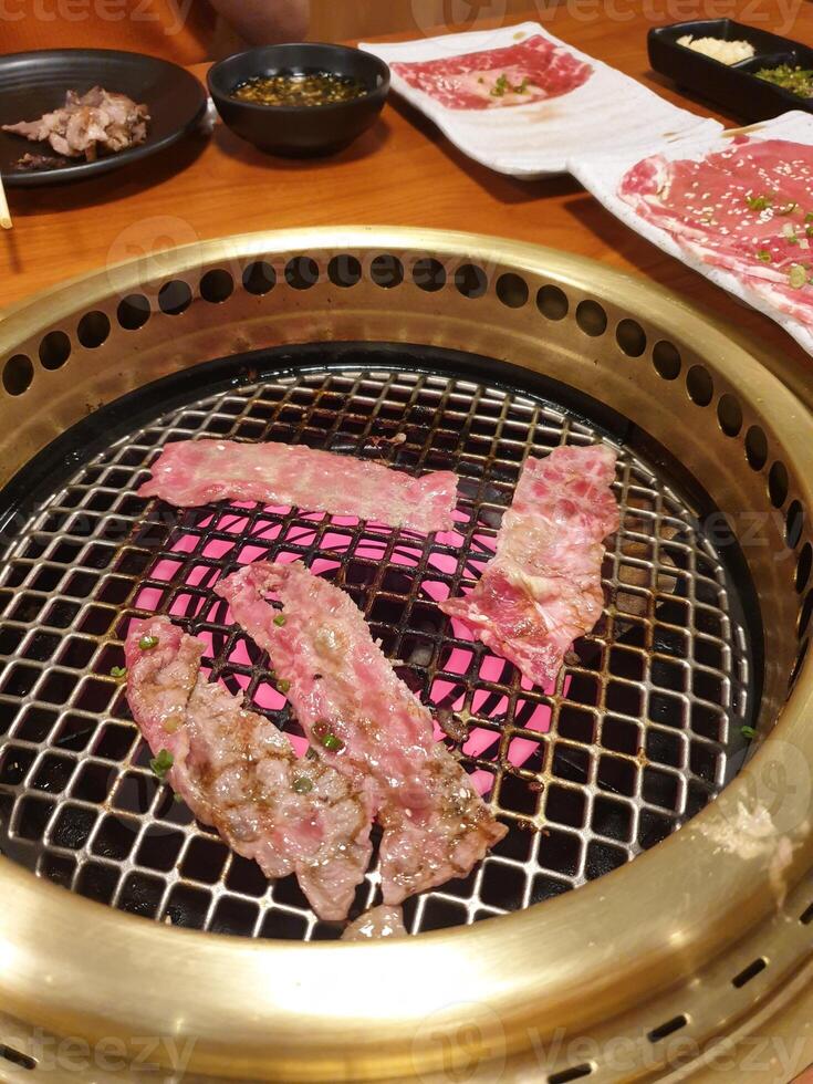 A grill with meat on it and a plate of food photo