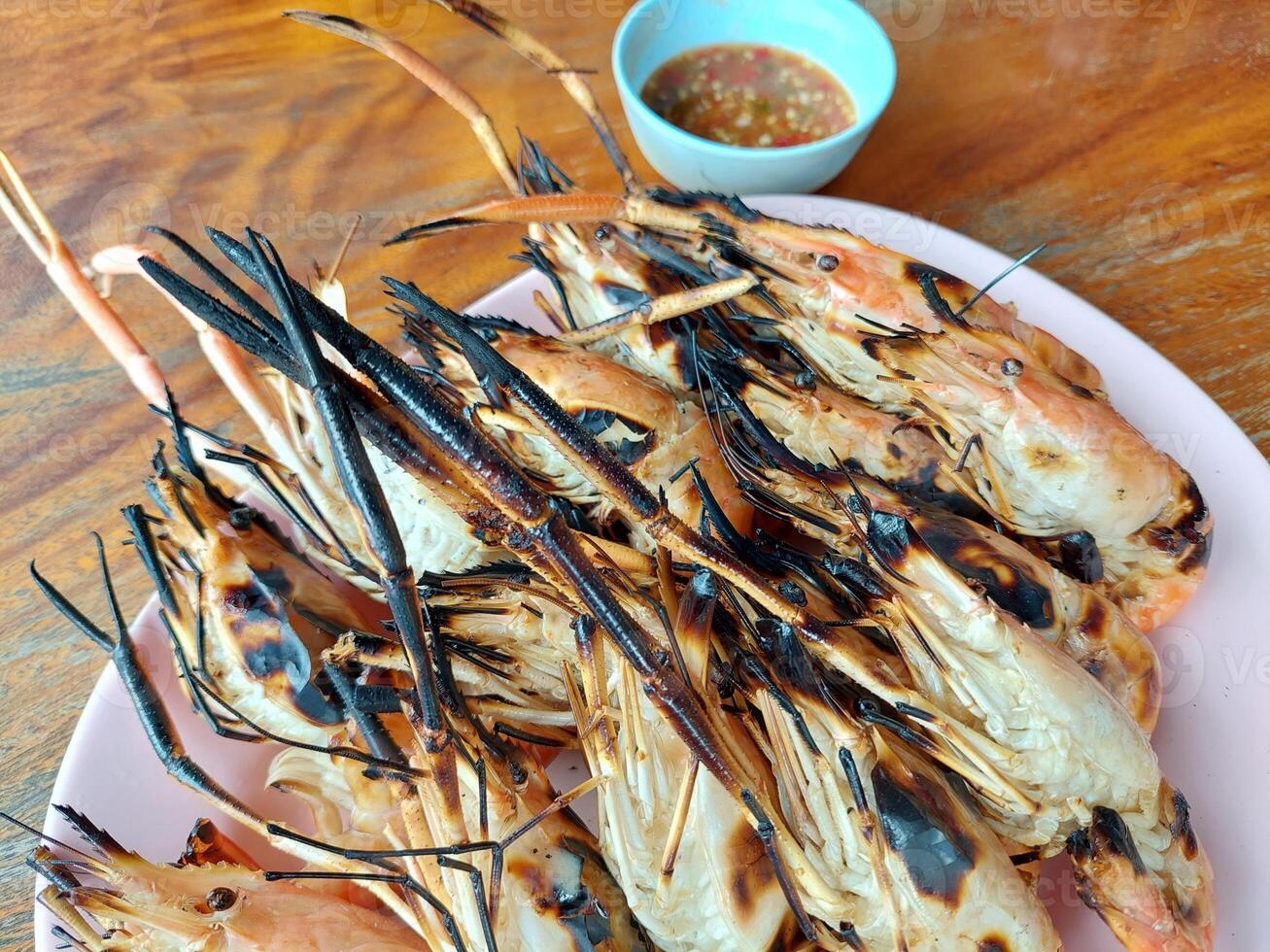 A plate of grilled shrimp on a wooden table photo